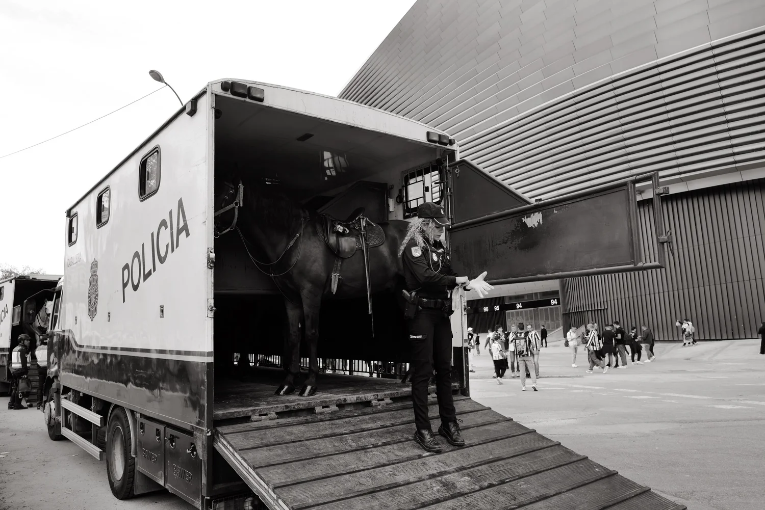 A mounted police officer prepares beside a horse trailer outside the stadium
