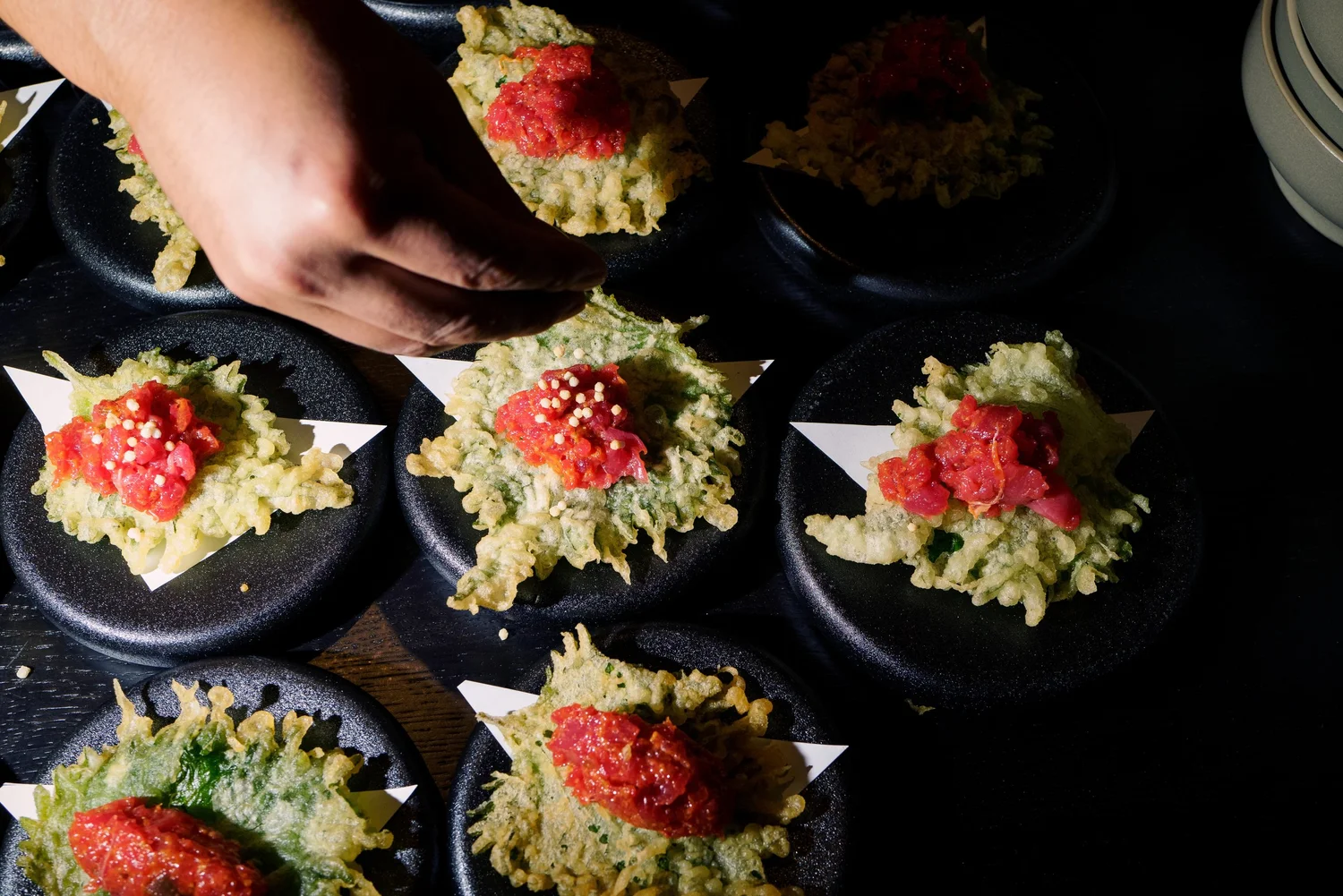 A chef finishing a row of dishes at Mizu