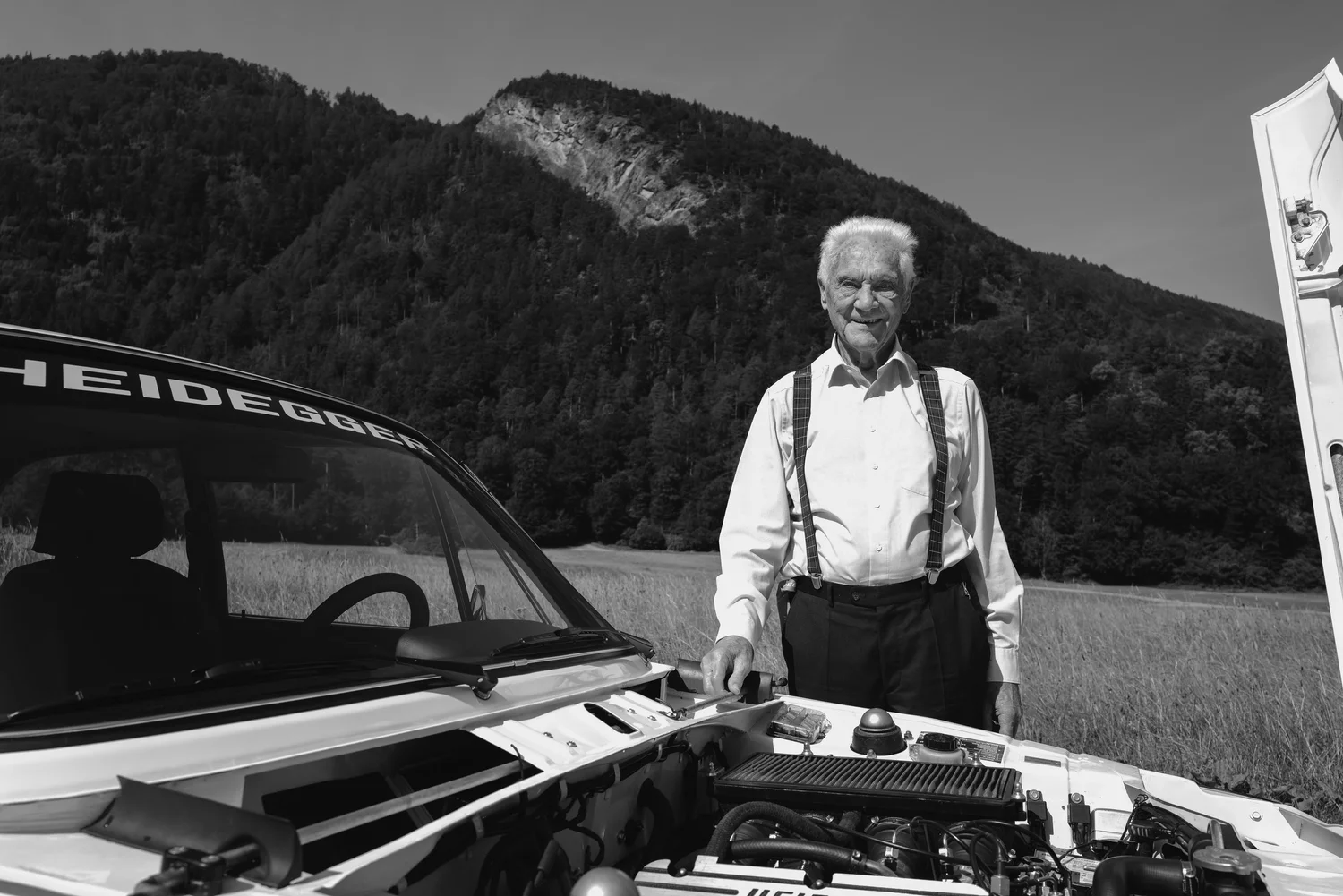 Portrait of an older man behind an open car bonnet at Max Heidegger