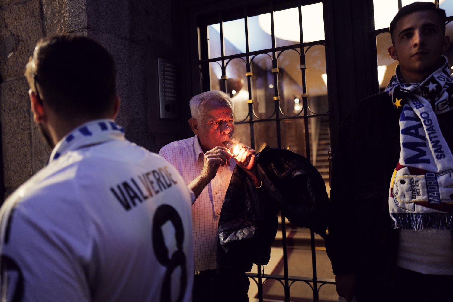 Supporters waiting outside a doorway in evening light