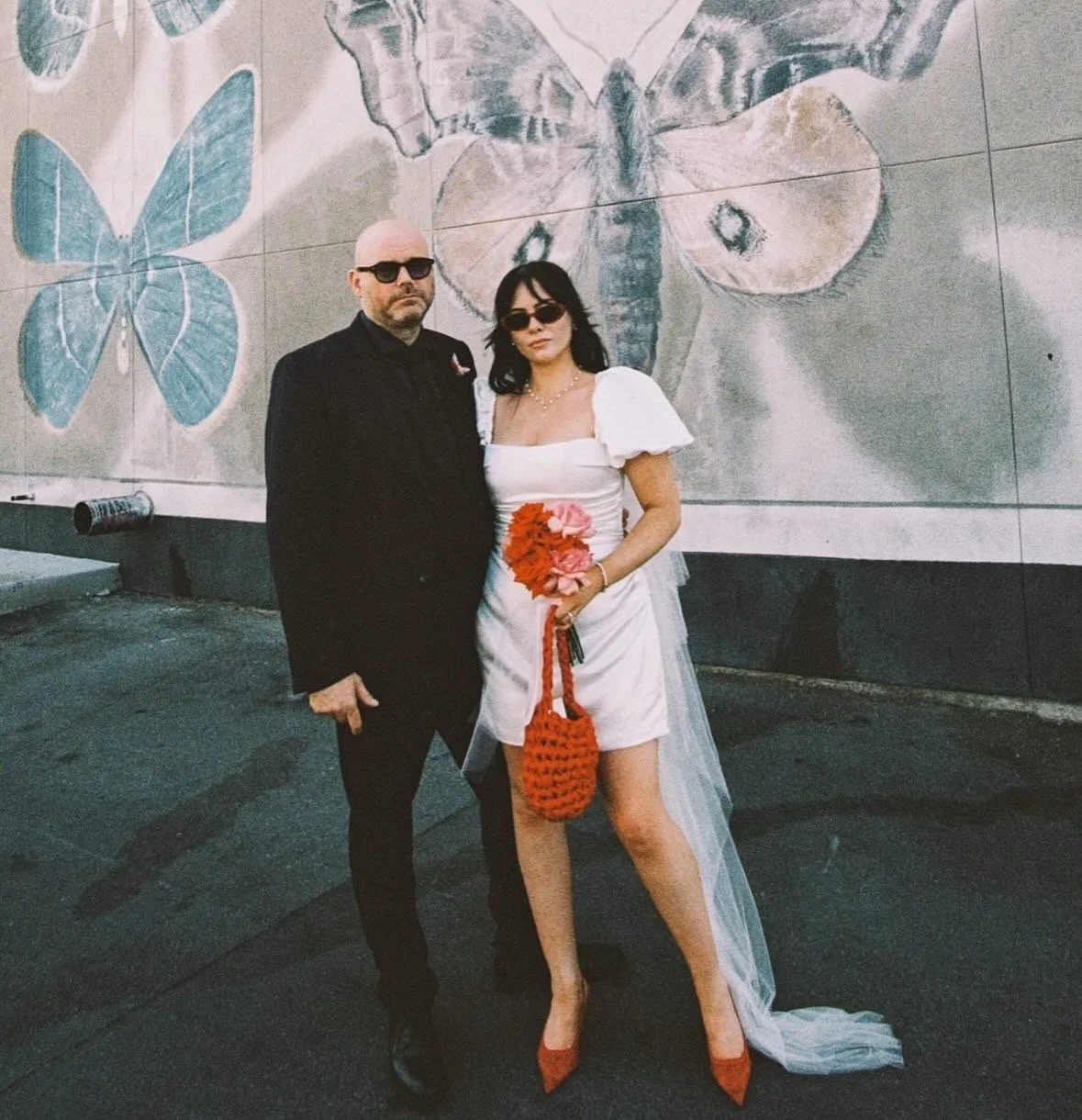 Real Bride wears a bespoke silk wedding dress for her Las Vegas elopement. It is a mini wedding dress with a corseted boned bodice, puff sleeves and lots of draping. Designed & made in Liverpool by high fashion wedding wear designer Emily Butler