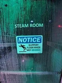 Glass entrance door to the steam room at The Works Indianapolis with illuminated lighting and fogged glass panels.