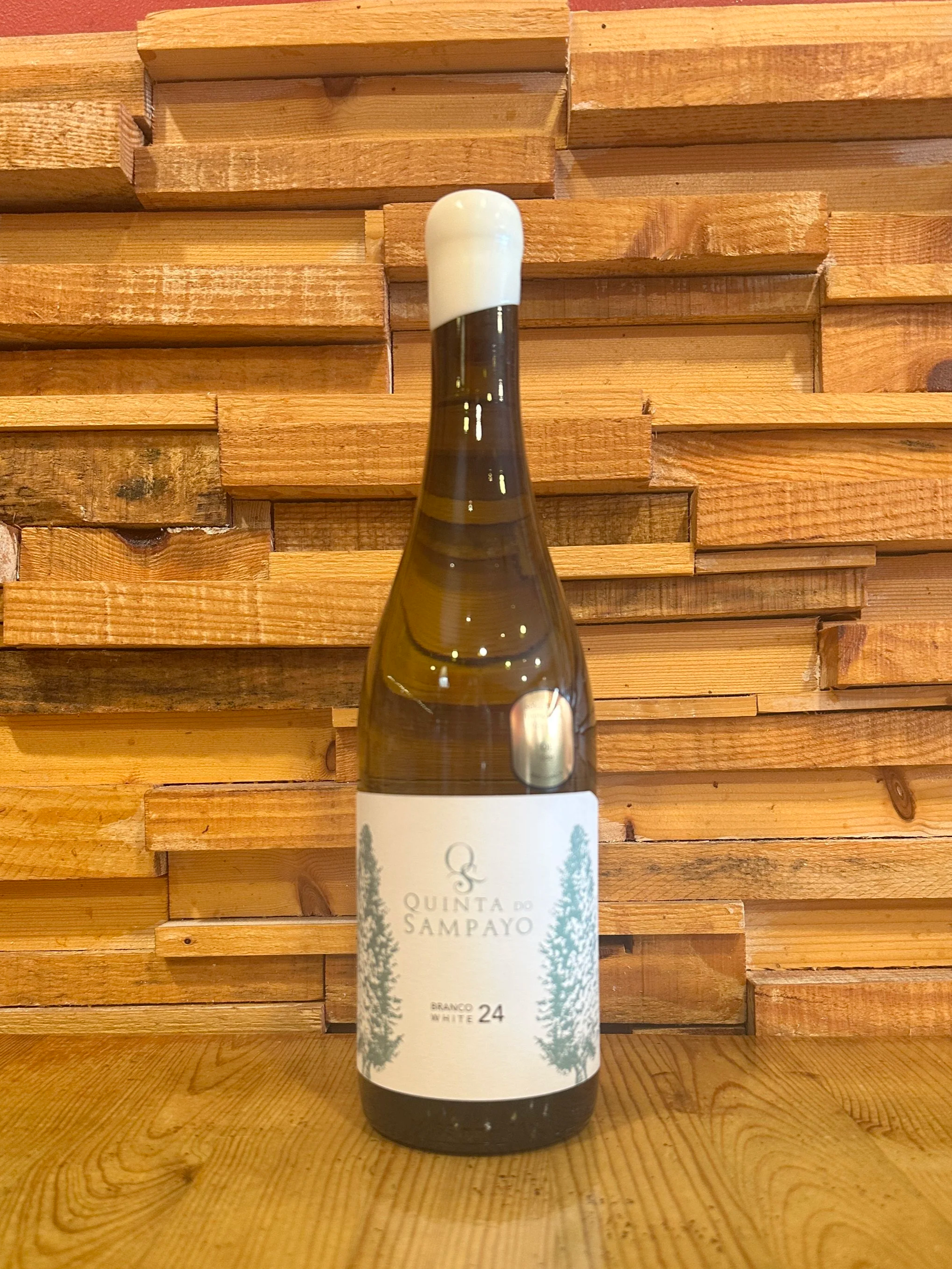 A bottle of Quinta do Sampayo Colheita wine on a wooden table with a wooden plank backdrop.