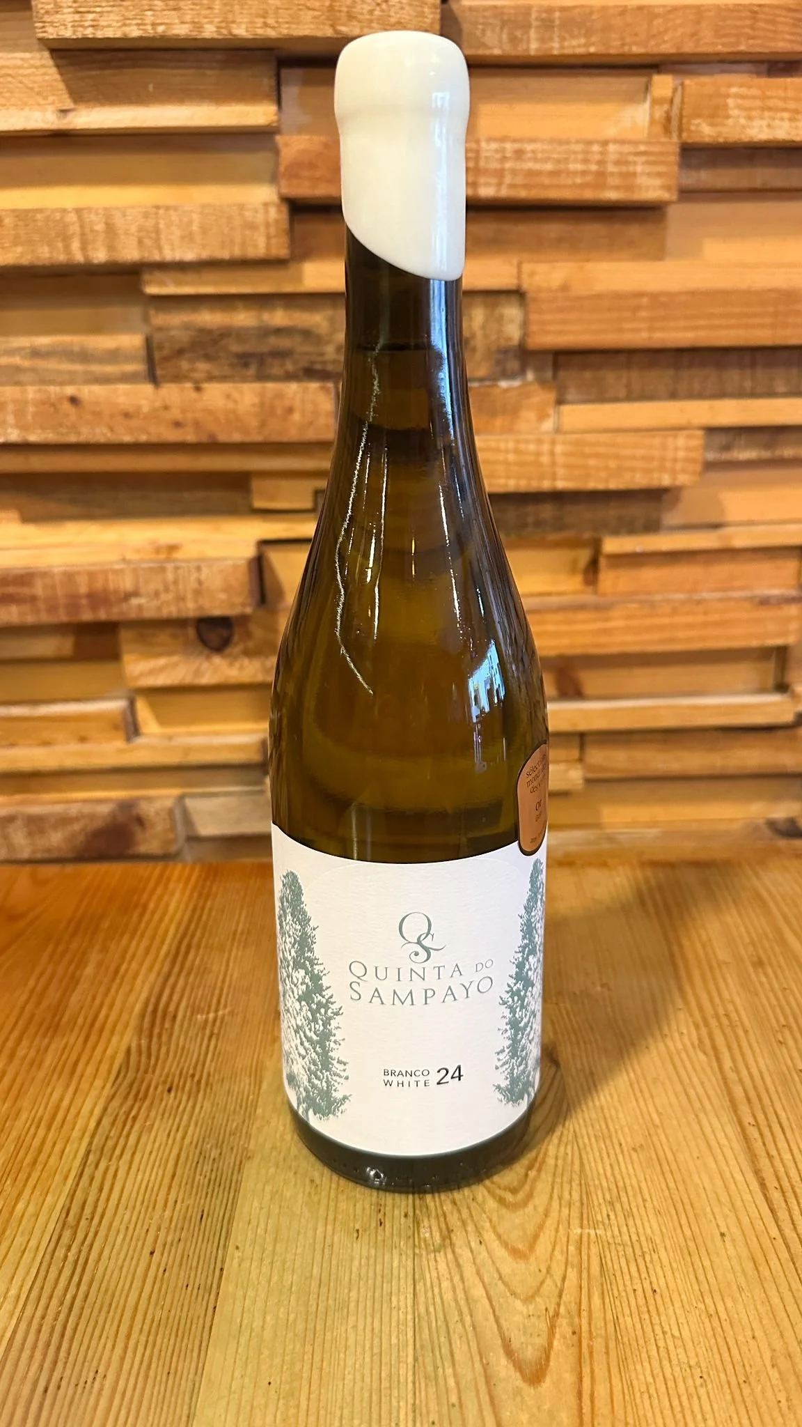 A bottle of Quinta do Sampayo Colheita wine on a wooden table with a wooden plank backdrop.