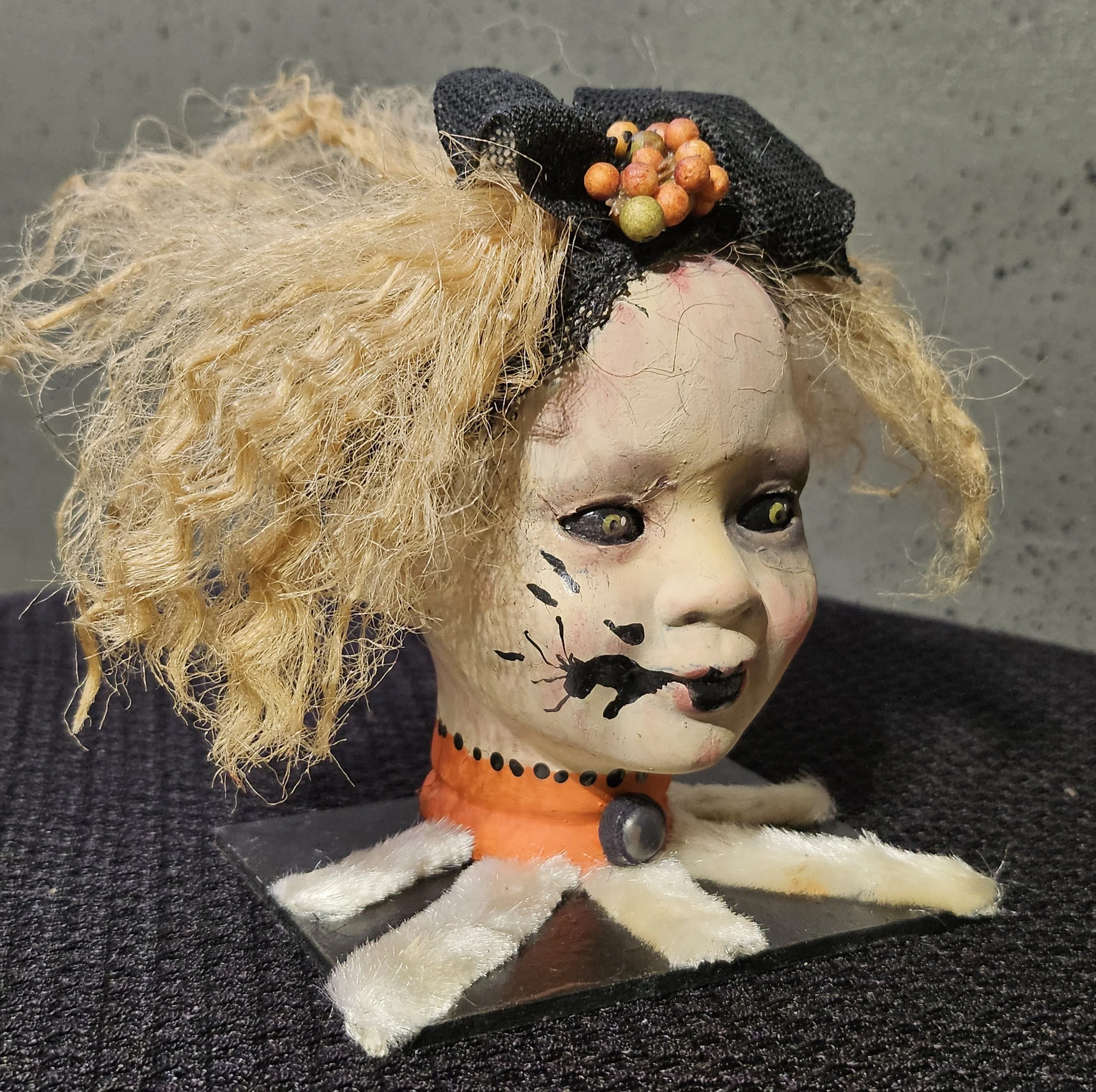  Right-side view of Ida showing her tangled blonde curls, crooked smile, facial scars, painted cracks, and black bow with autumn-colored berries. 