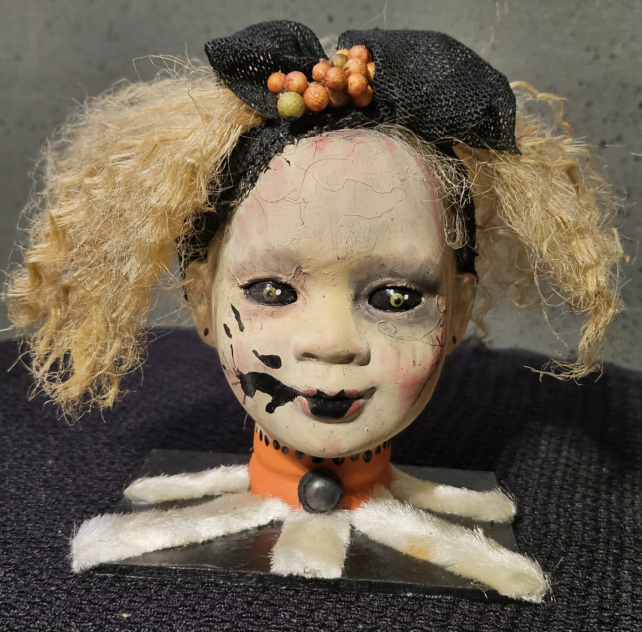  Front view of Ida, a handmade gothic doll with wild blonde curls, cracked pale skin, stitched scars, black lips, and a crooked smile. 