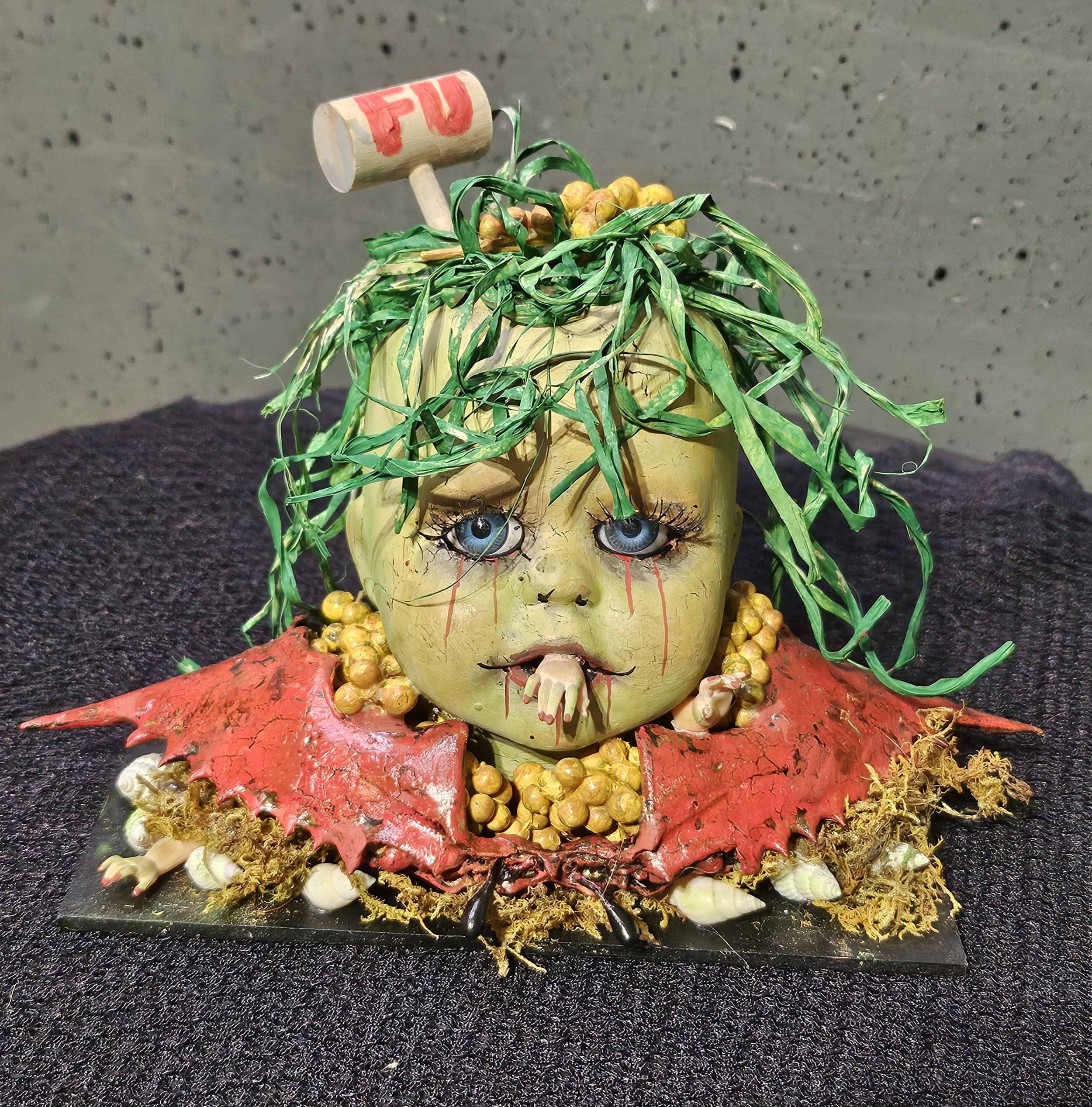  Front view of The Last Crab Boil, a sea-creature horror doll with blue eyes, seaweed hair, tiny claws, crab mustard, a shattered shell, and an FU mallet. 