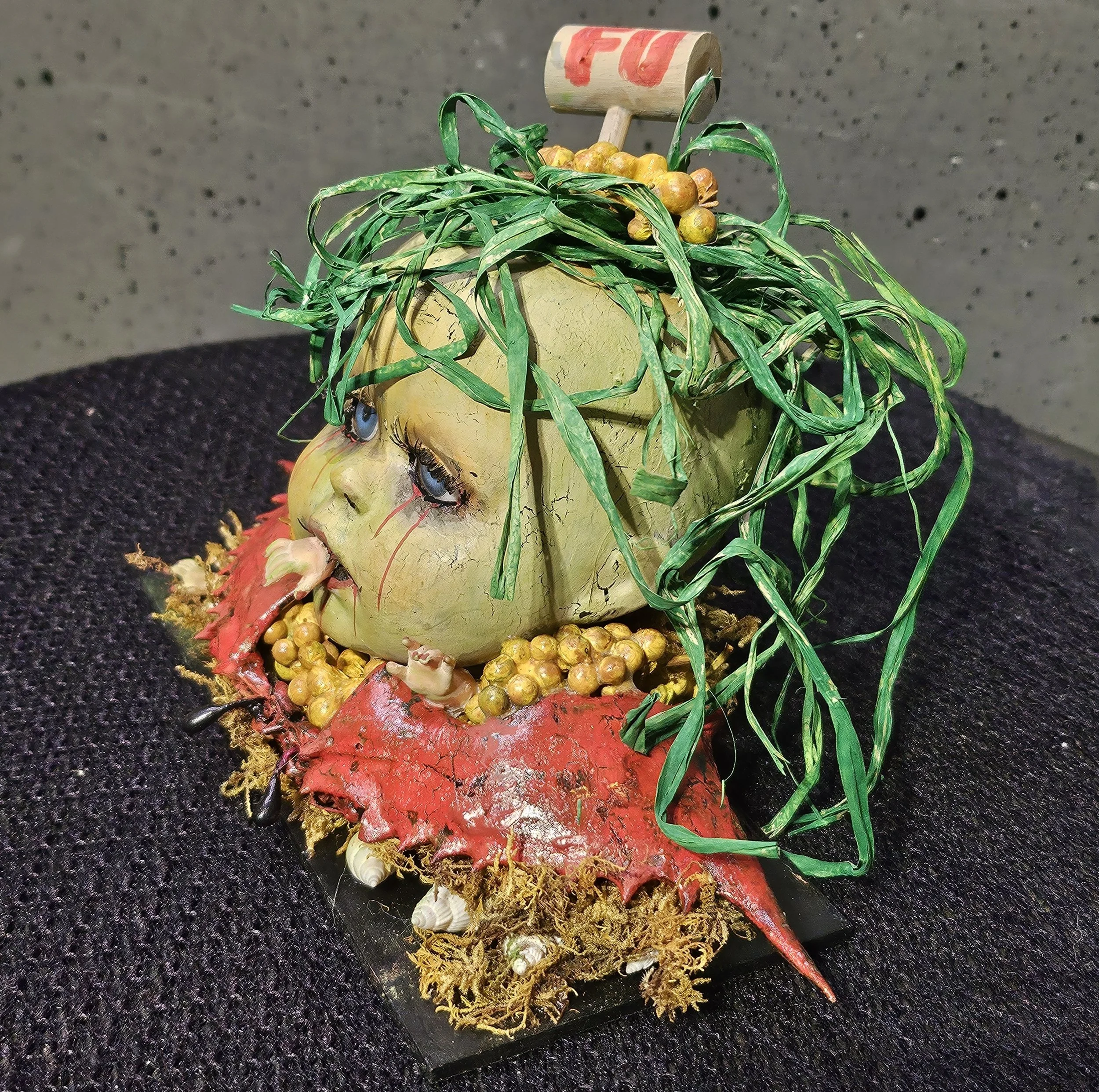  Left-side view of The Last Crab Boil, a handmade recycled doll with seaweed hair, blue eyes, tiny crab claws, crab mustard, shells, and a broken red crab shell. 