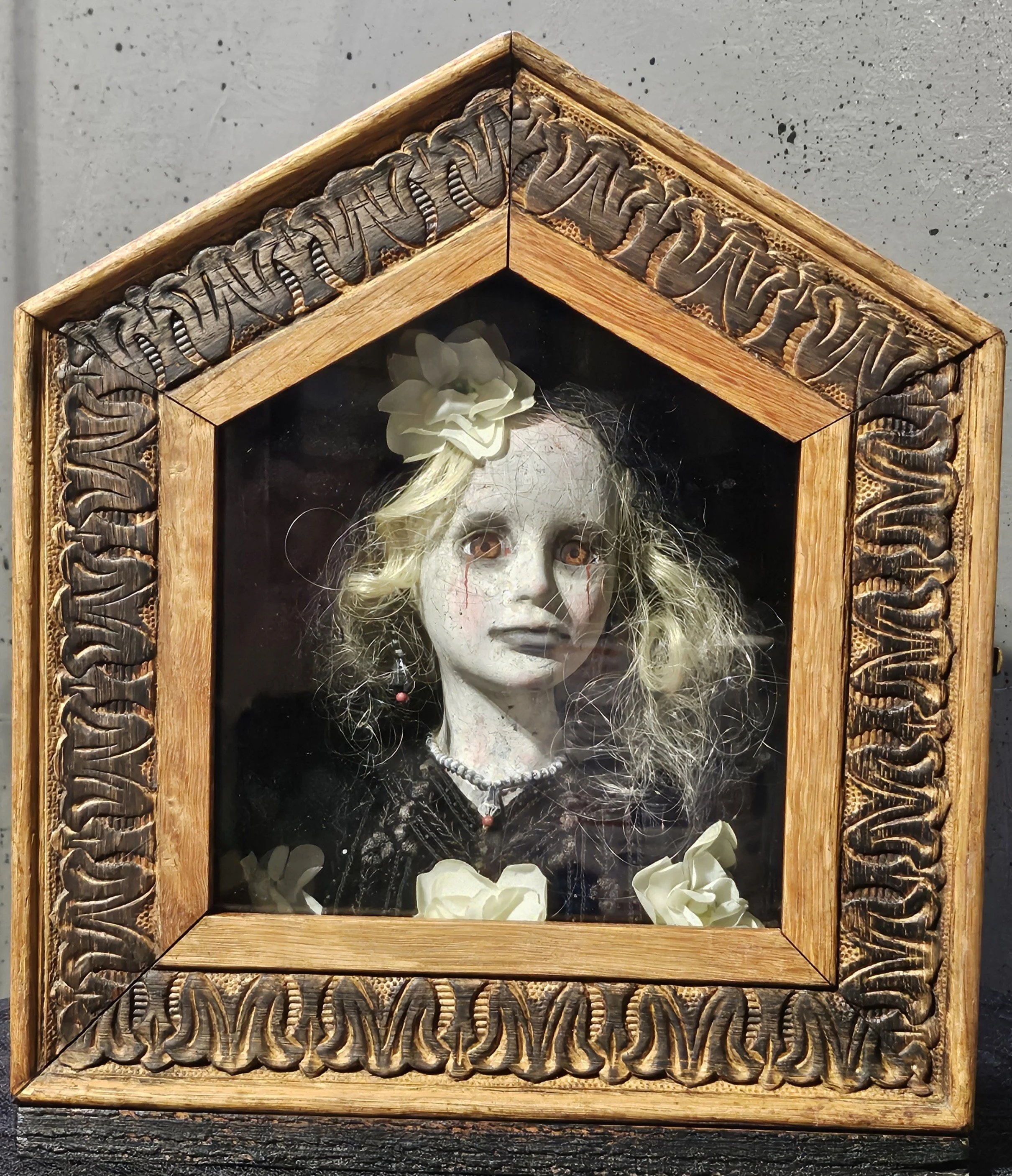  The Mourning House, a handmade gothic doll with tangled blonde hair and amber eyes, dressed in black among white flowers inside a carved vintage clock case. 
