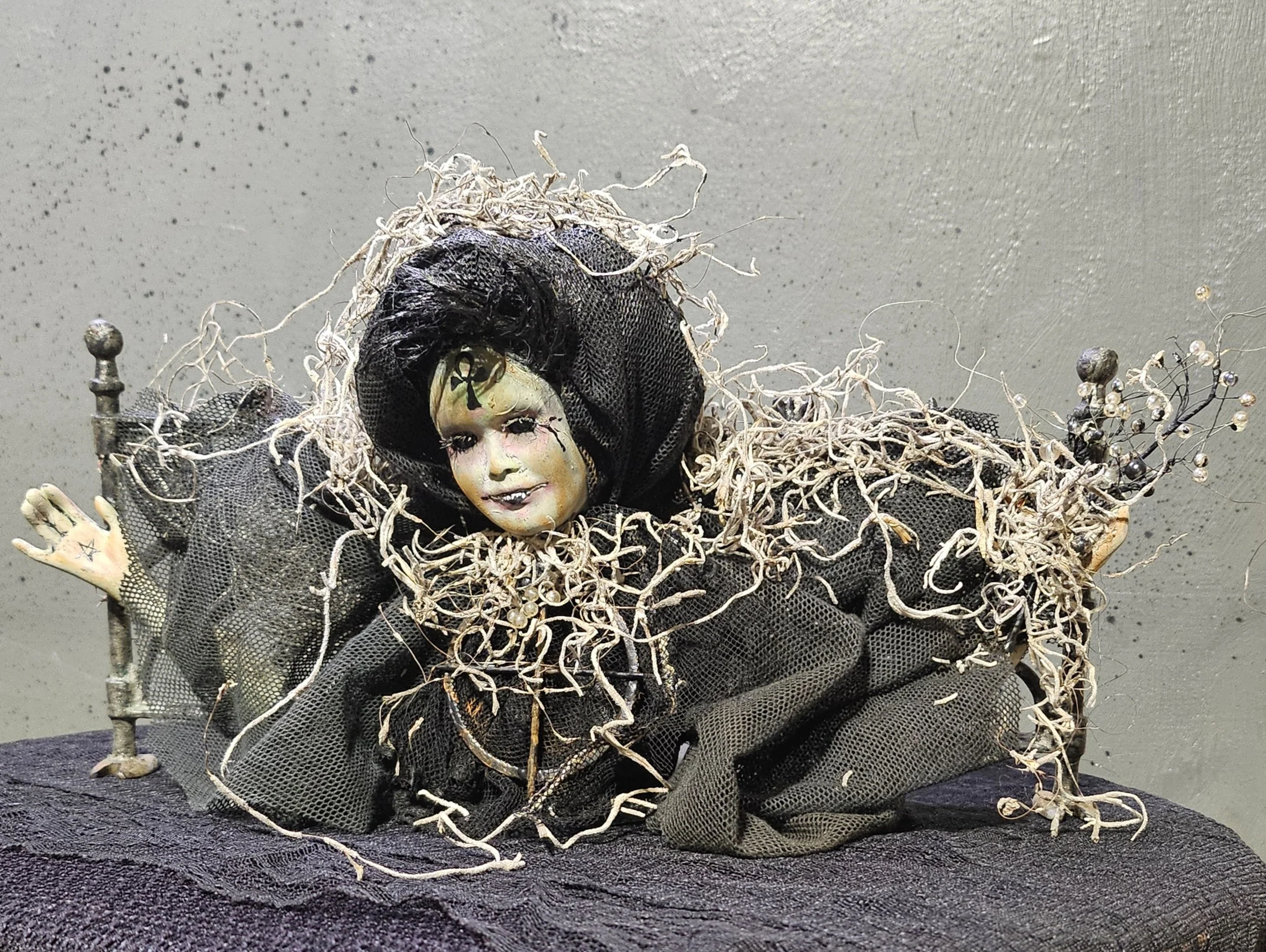  Right-side view of Fence Line Hex showing her crooked smile, tangled black veil, moss-covered clothing, outstretched hands, and beaded branches. 