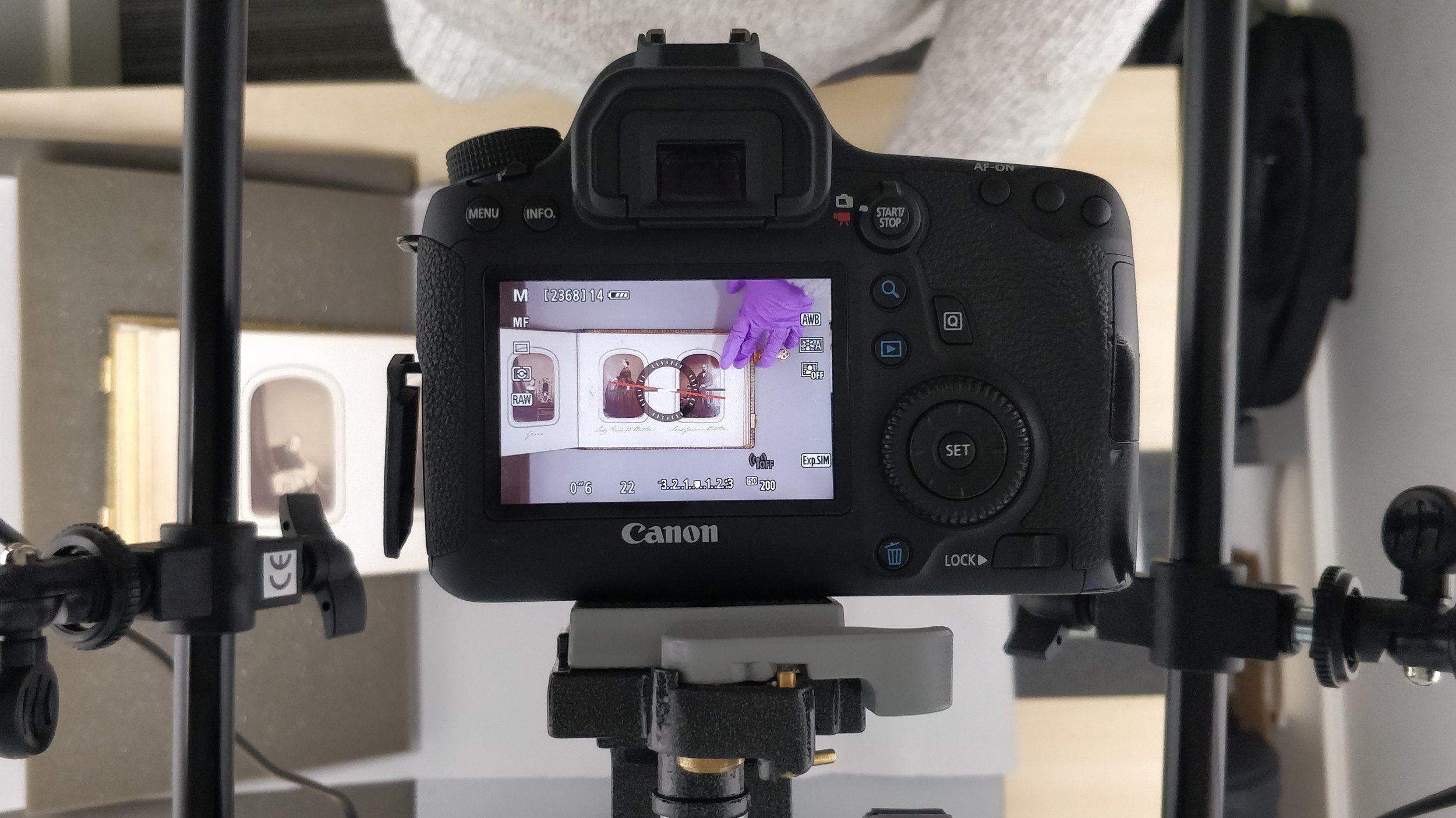 A camera monitor showing an old photograph album, with two carte de visites showing women.