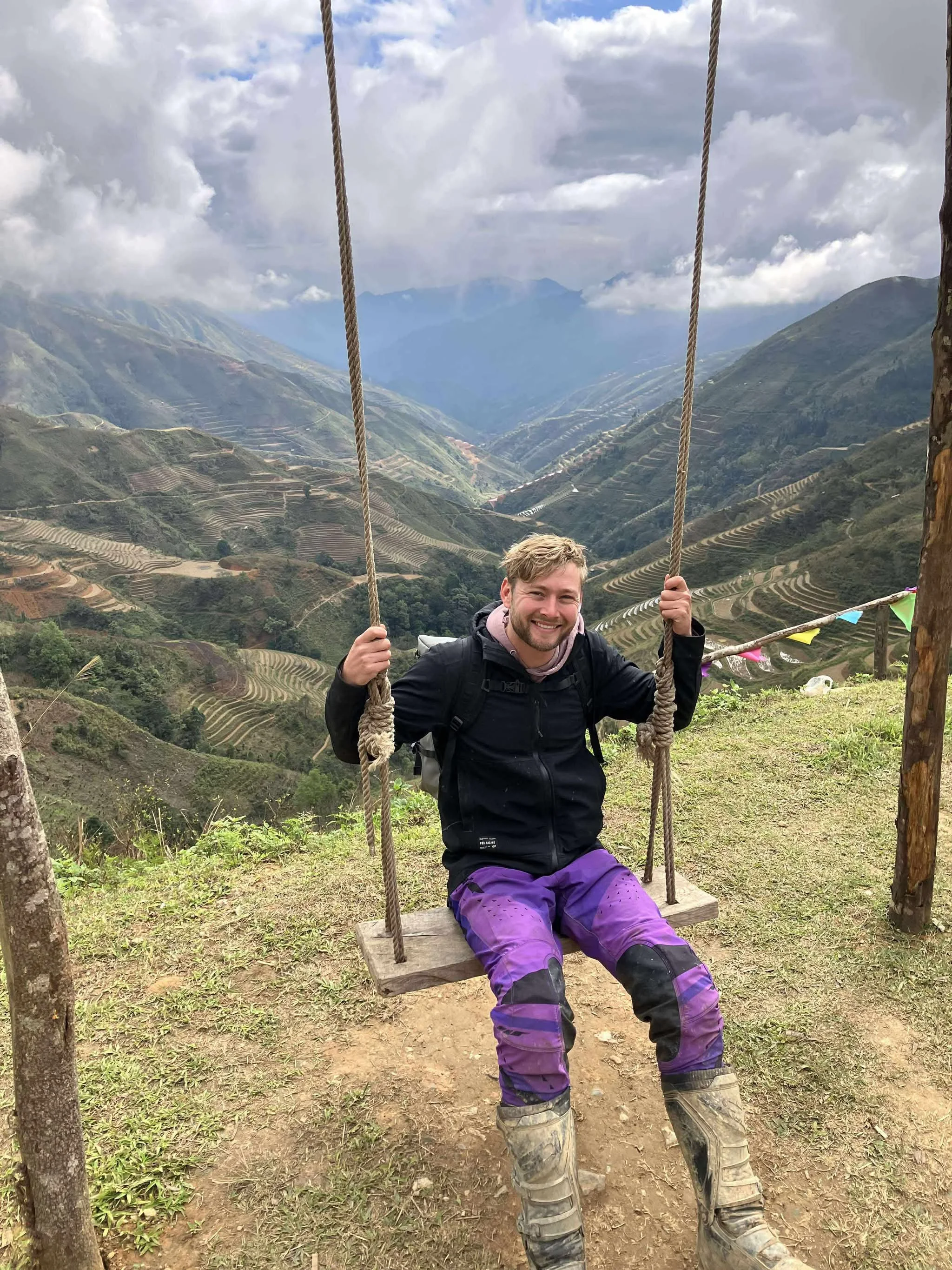 Tour guide sits on a swing at a mountaintop in Ta Xua on an off-road tour