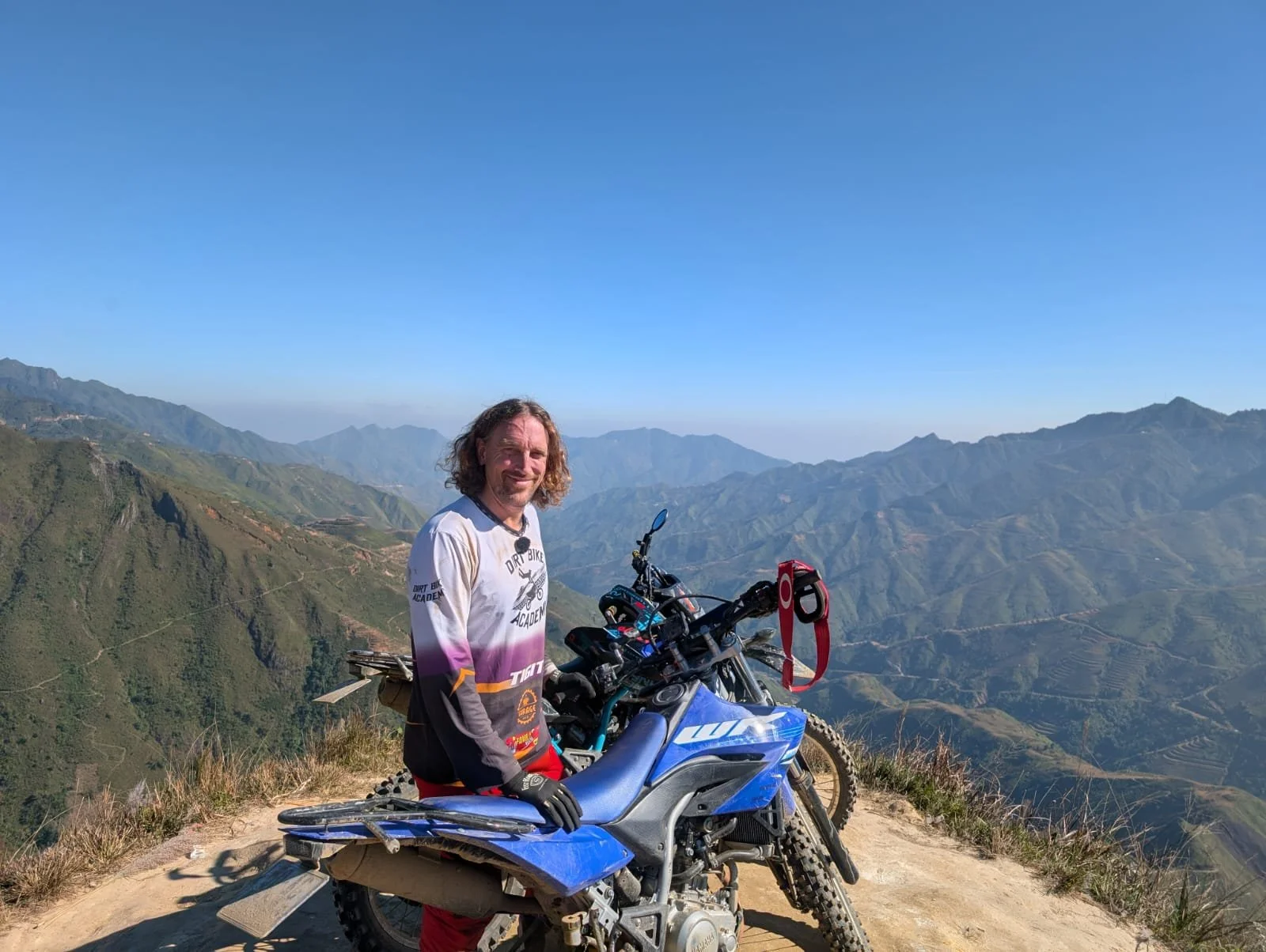 Customer poses with a WR 155 on a mountain ridge with blue sky