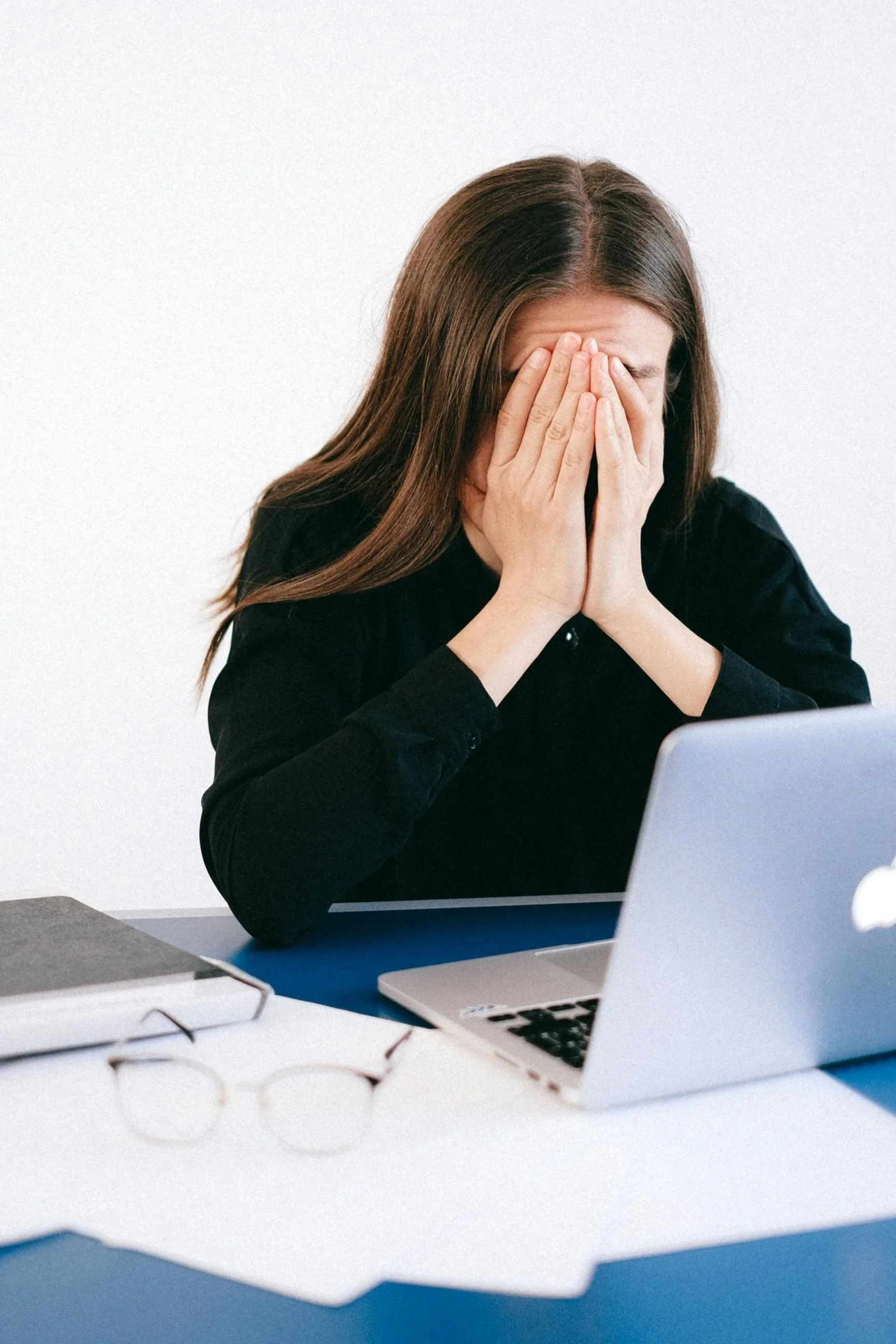 woman in front of computer, stressed at work and covering her face