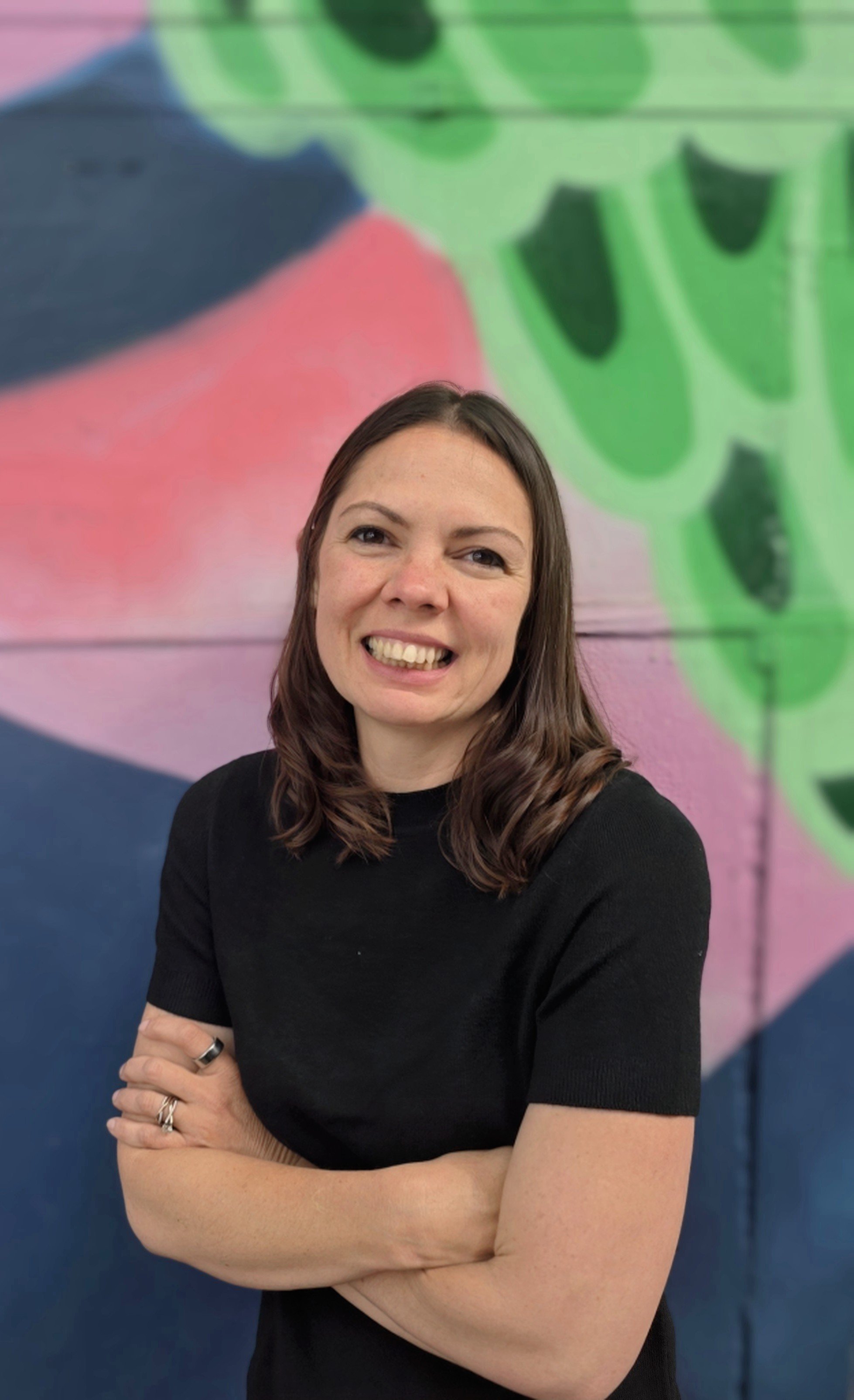 Kelly Grover, LPC, therapist at Driftline Counseling, smiling in front of a colorful abstract background in Portland, OR