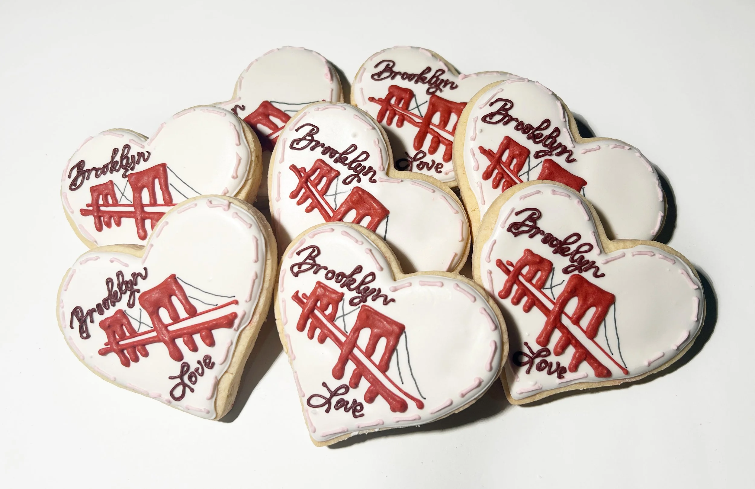 Heart-shaped cookies decorated with white icing, red and black icing, featuring the Brooklyn Bridge and words "Brooklyn" and "Love."