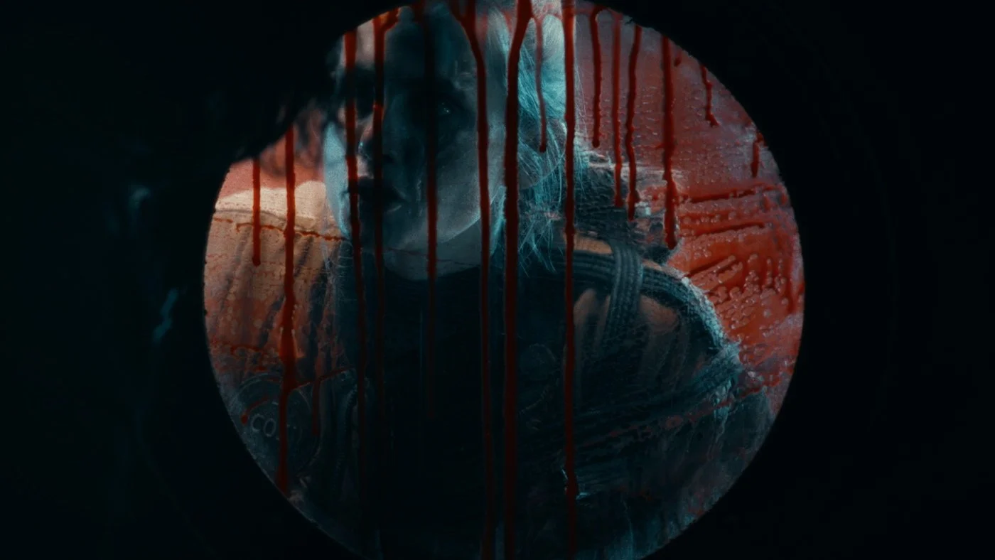 Caroline Kaplan as "Ava" outside the porthole of the sub. It's dripping blood.