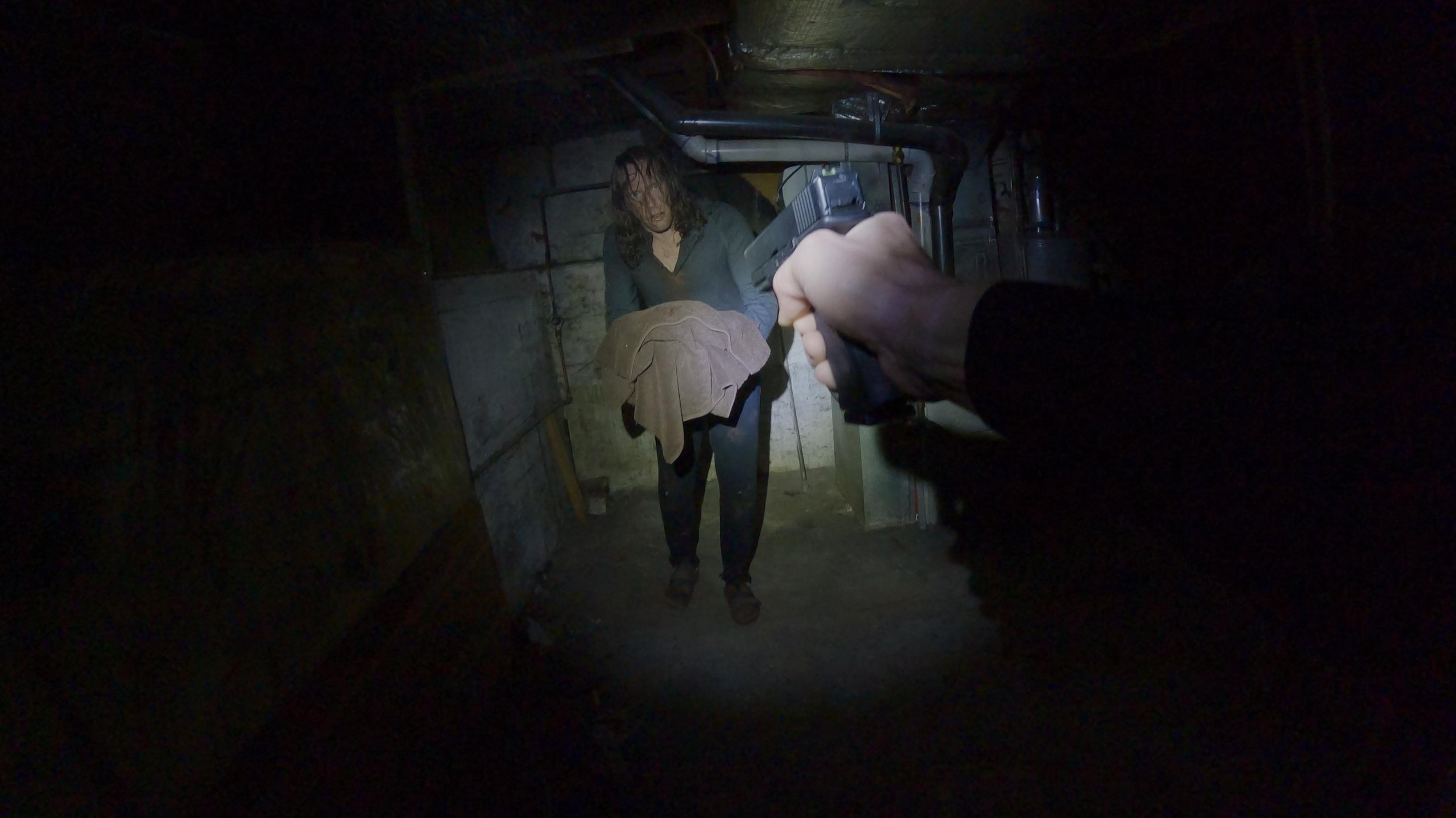 Bryce brandishing his pistol at a man holding a bundle of towels