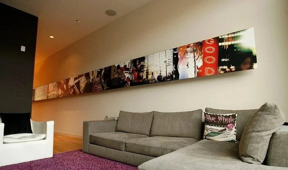 Modern living room with a gray sofa, a white armchair, a purple rug, and a long colorful abstract artwork on the wall.