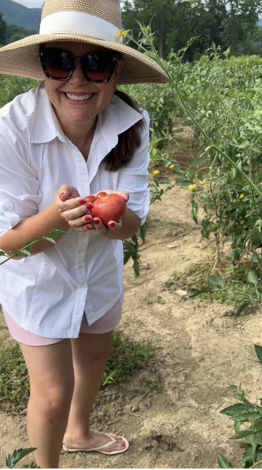 Carmen Johnston holding ripe tomatoes in a field