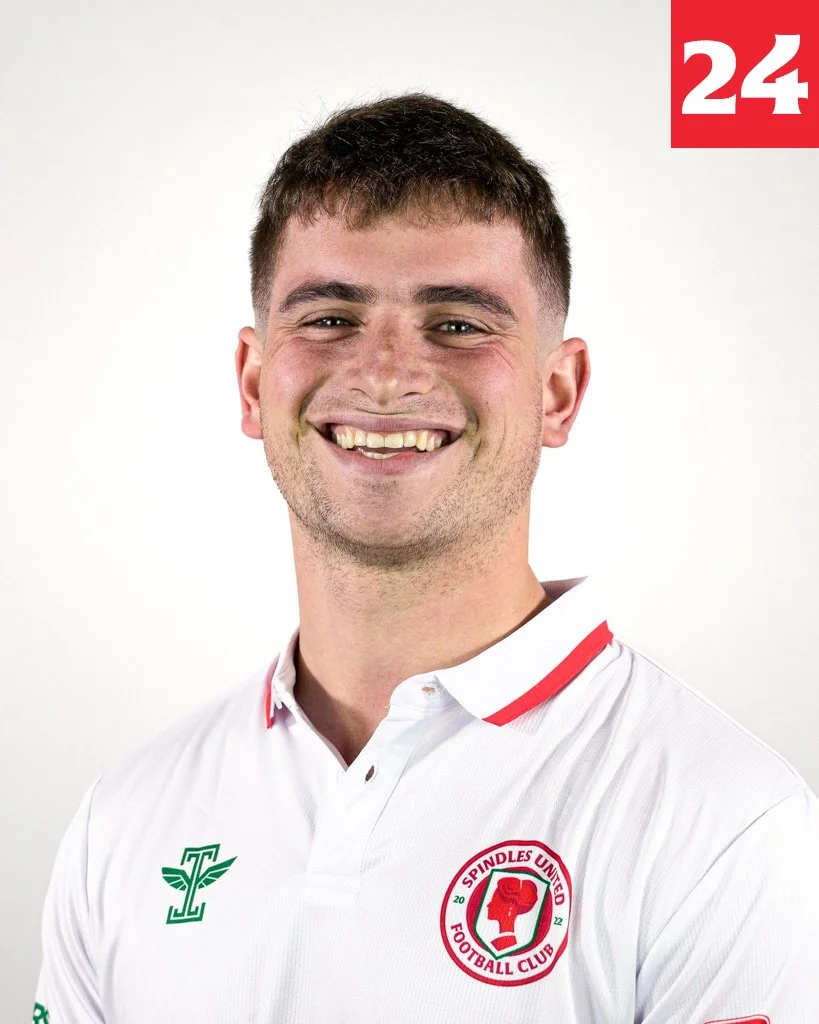 A young man smiling, wearing a white football jersey with the Spindles United Football Club logo on the chest. The logo features a red fist within a circular red border, and a green letter 'T' with wings on the left side of his chest. The background is plain white, and the number 24 is in the top right corner in red with white numerals.