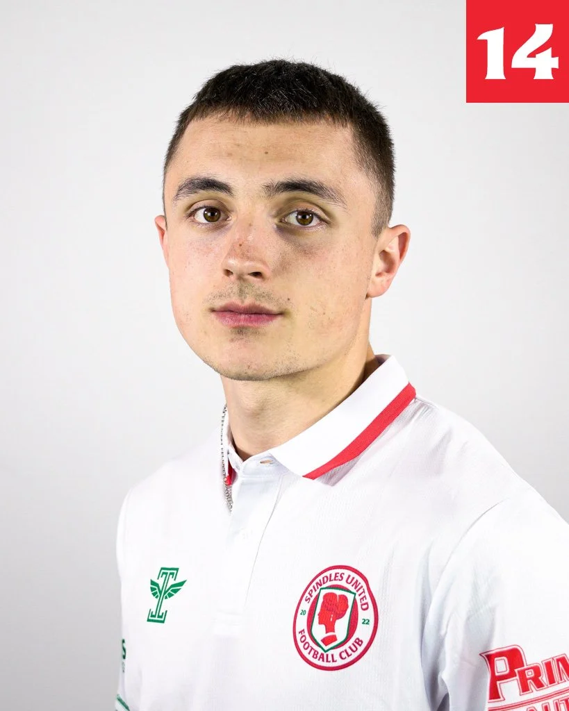 Young man wearing a white football jersey with green and red logos, and a red number 14 in the top right corner.