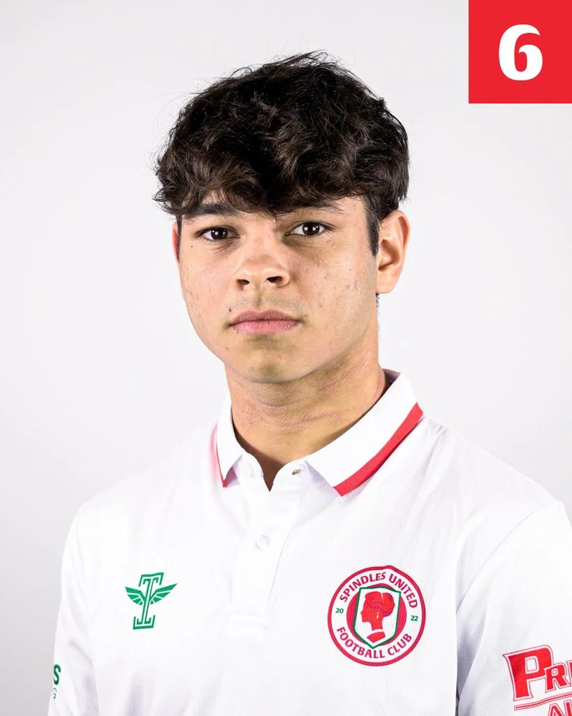 Portrait of a young man with dark, wavy hair wearing a white sports polo shirt with logos for Spindles United Football Club and other sponsors.