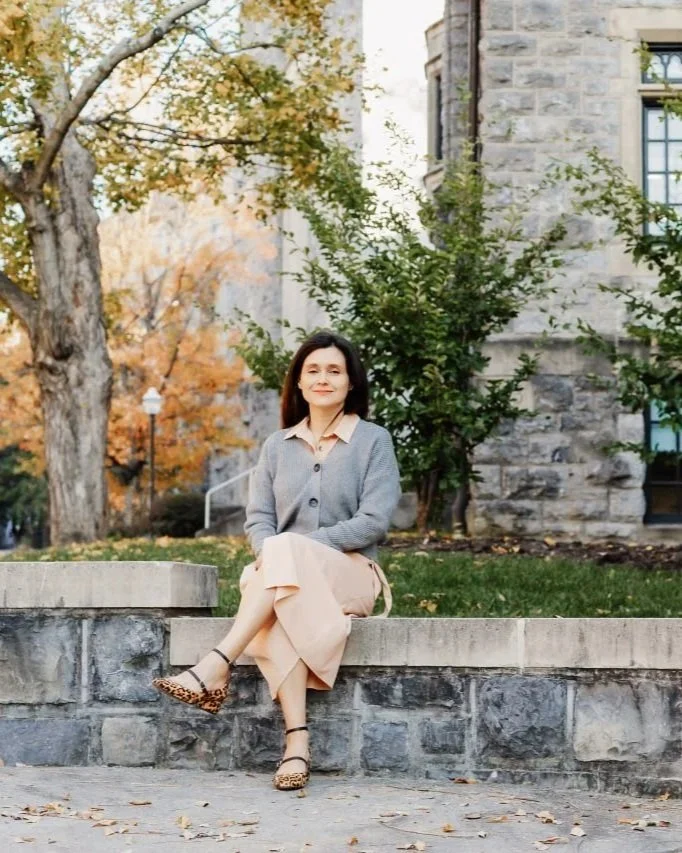 Melissa Tully licensed counselor virginia seated on a bench outside a buildingwearing a pink skirt and grey cardigan