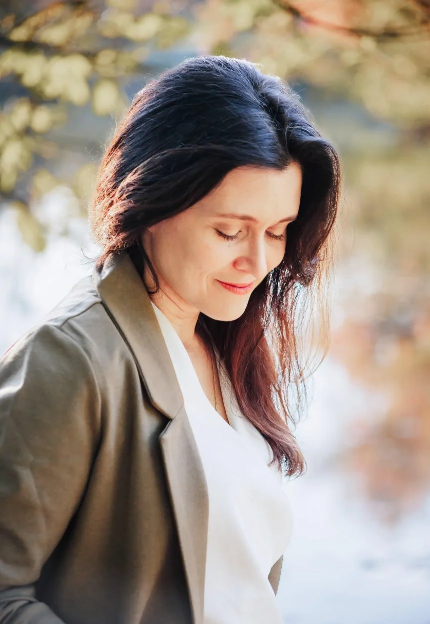 somatic therapist in virginia Melissa Tully looking down standing in front of foliage