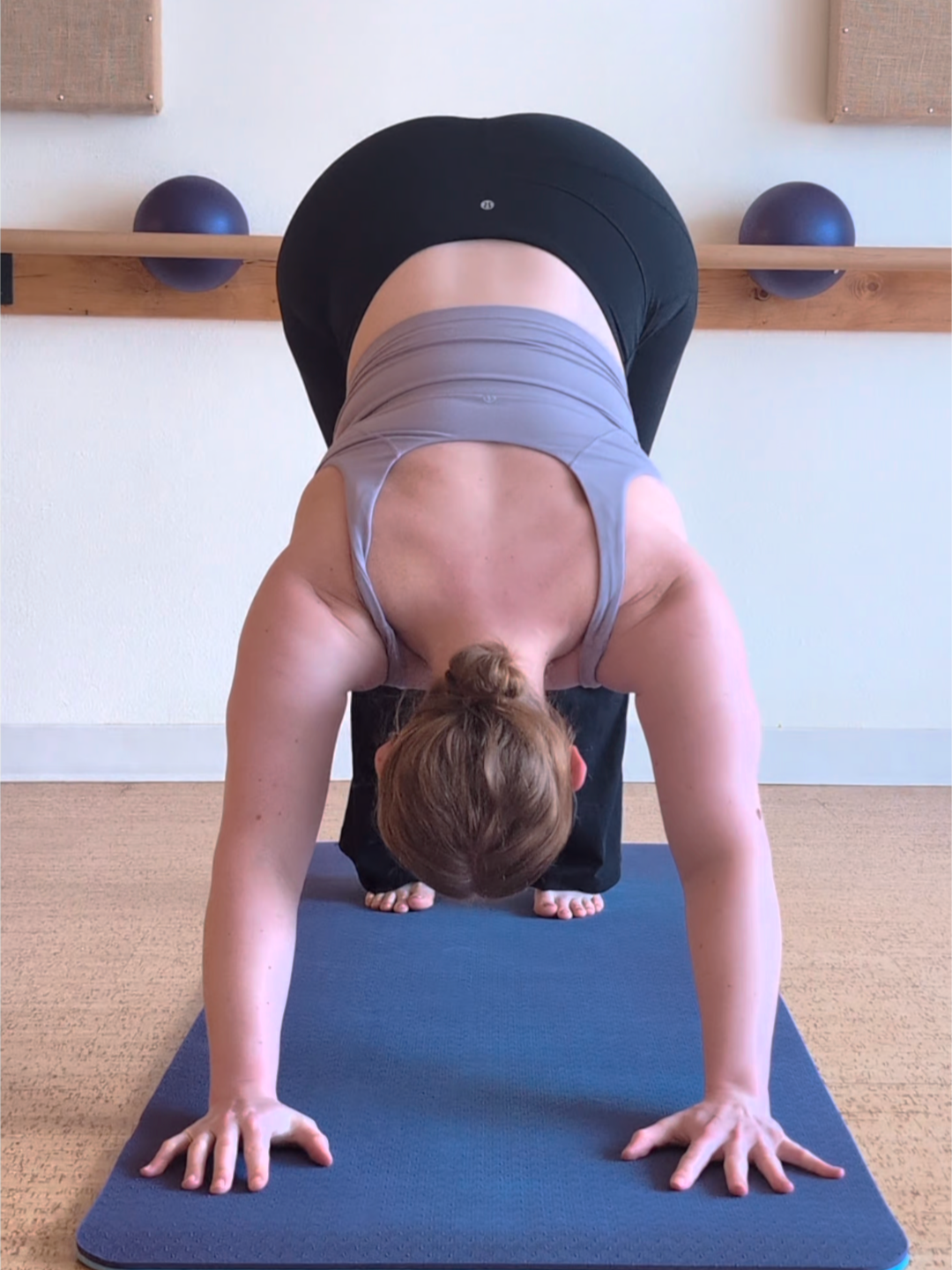 Woman on a purple yoga mat performing a downward facing dog.