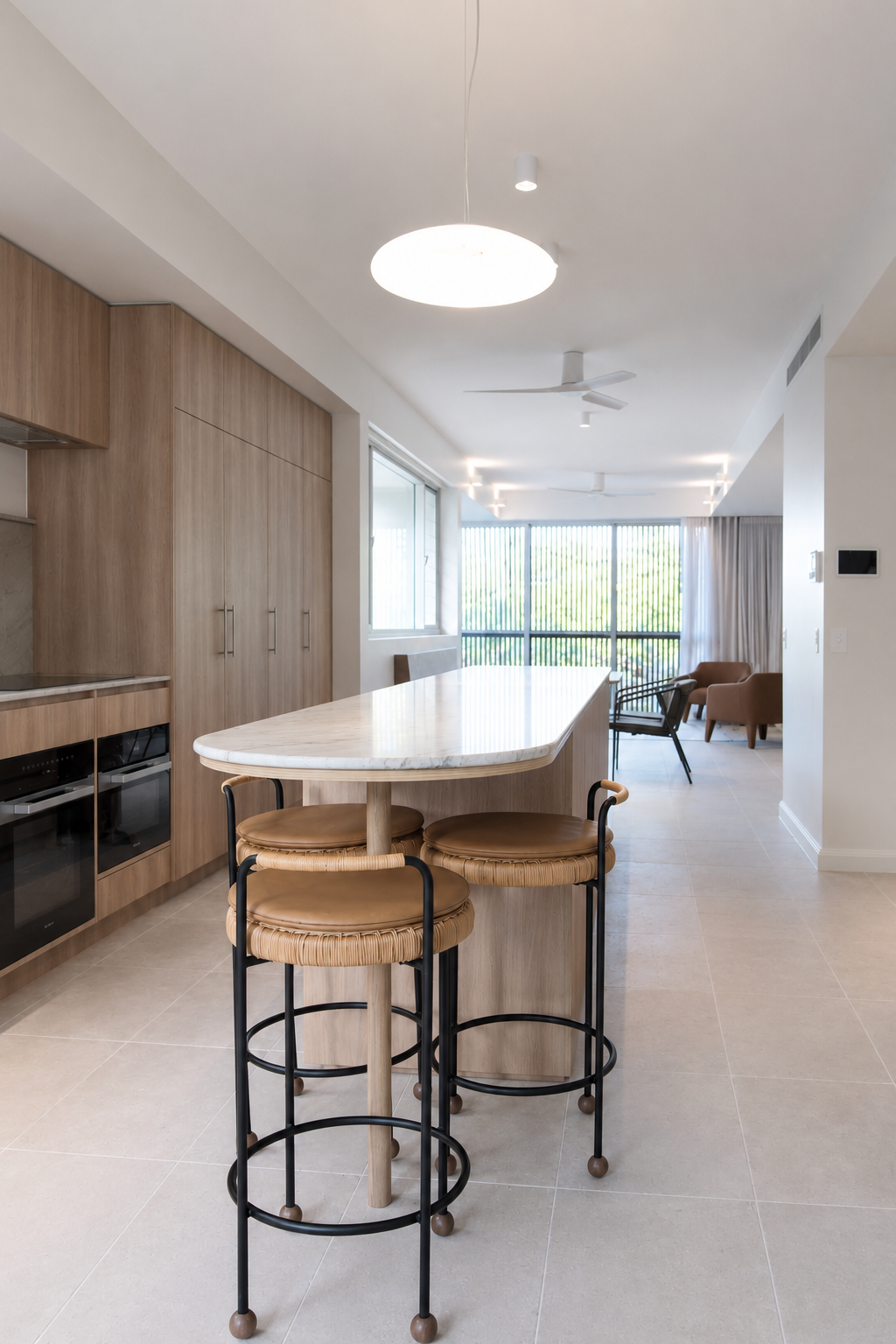 Modern or contemporary kitchen and living space with a marble-topped breakfast bar, three bar stools, and natural light from large windows with vertical blinds.