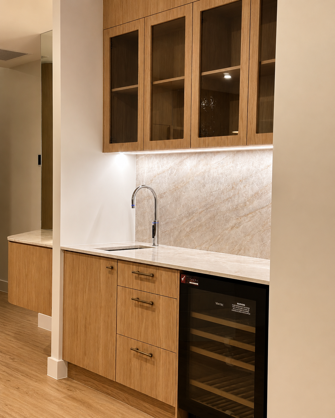 Modern kitchen with wooden cabinets, a marble countertop, a small sink, and a wine cooler.