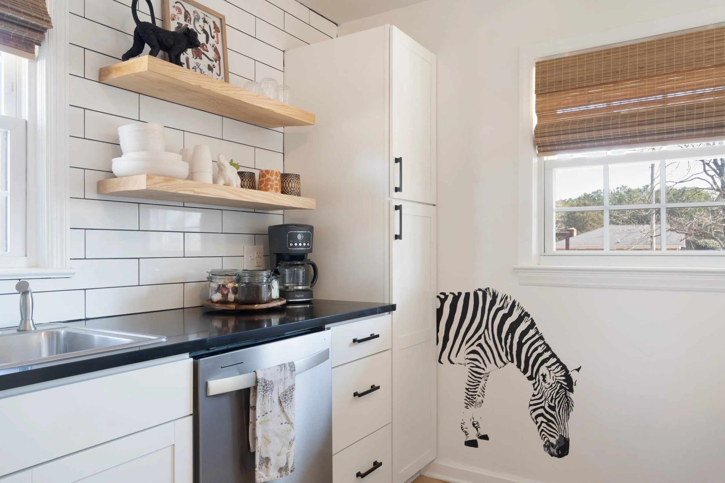 A white ceramic mug on a wooden tray next to a blanket or quilt, near a window with blinds.