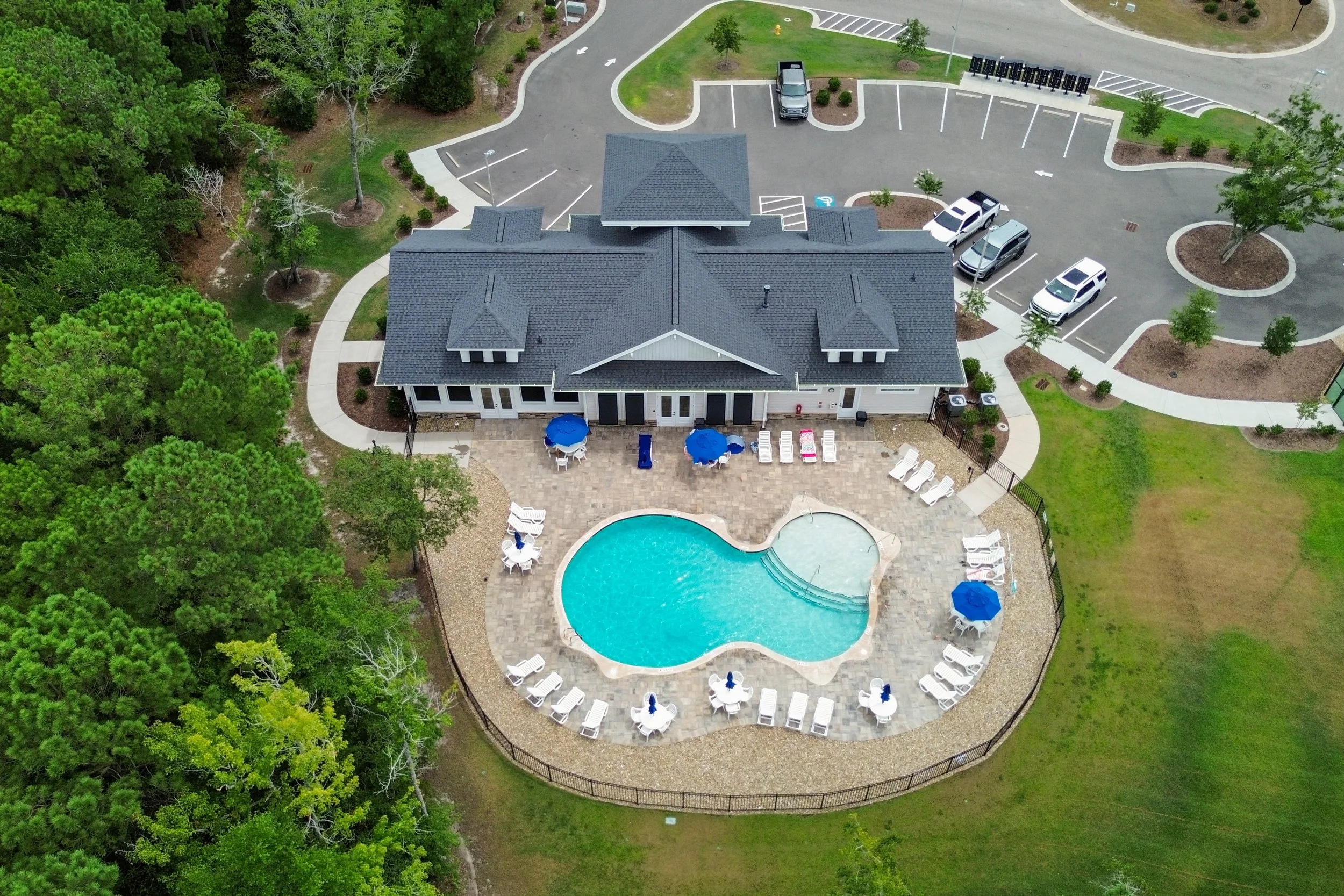 Swimming pool area with lounge chairs and umbrellas, overlooking a river with trees on the opposite bank.