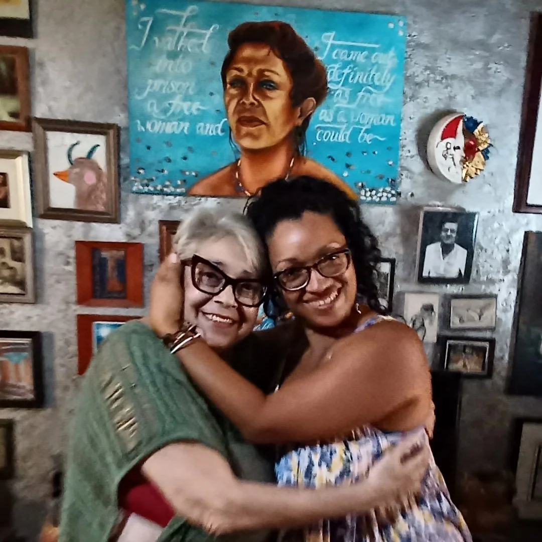 Yasmín con su querida amiga, mentora, matriota (y ahora ancestra) Dylcia Pagán y su retrato. En casa de Dylcia, Loíza, PR.