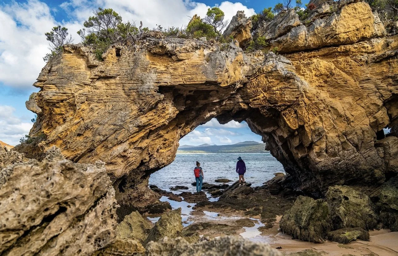 Things to do on Flinders Island | Flinders Island Aviation | Pair standing under rock on Tasmanian Expeditions trip