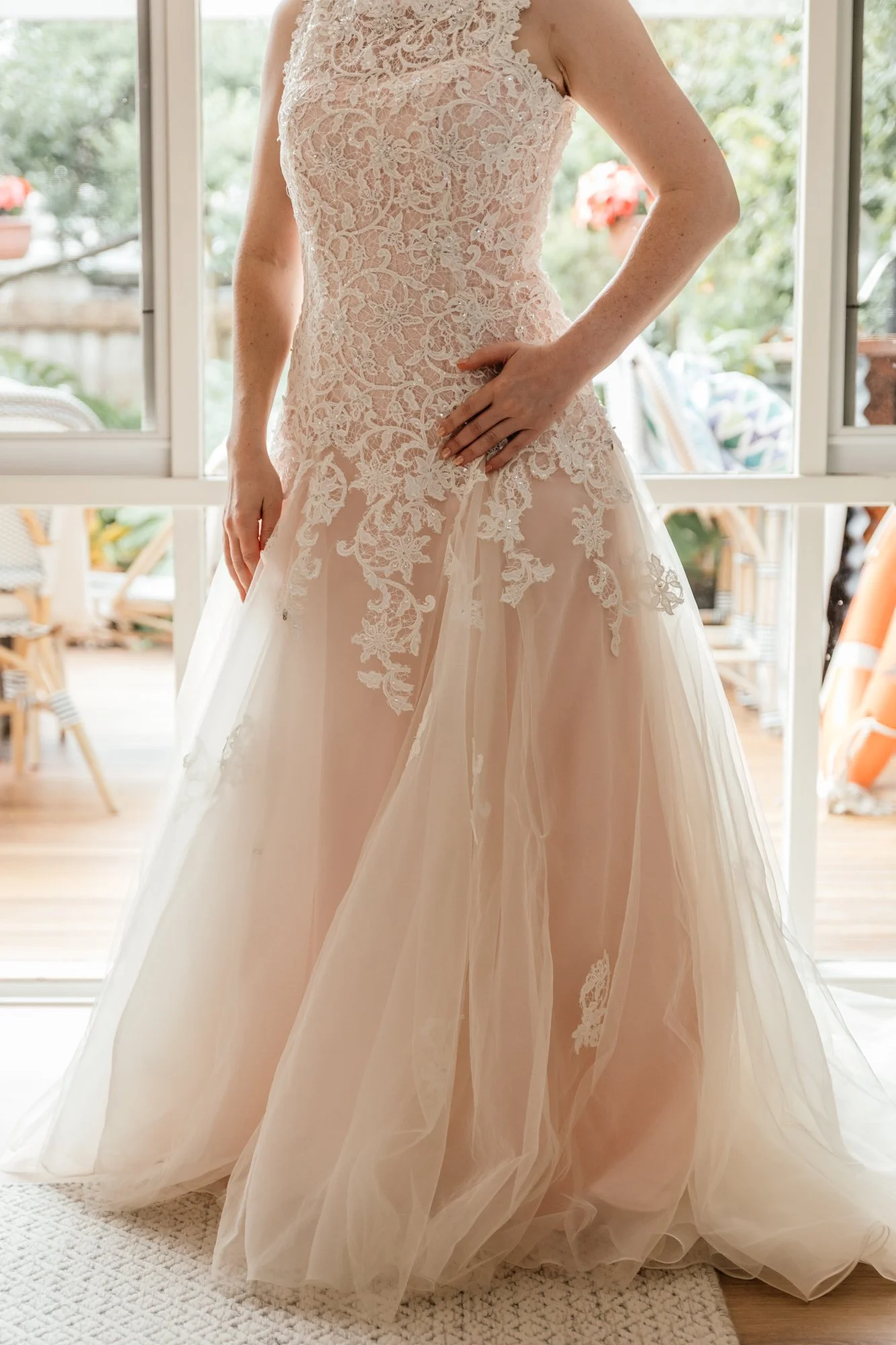 Wedding dress with lace bodice and tulle skirt, worn by a bride indoors.