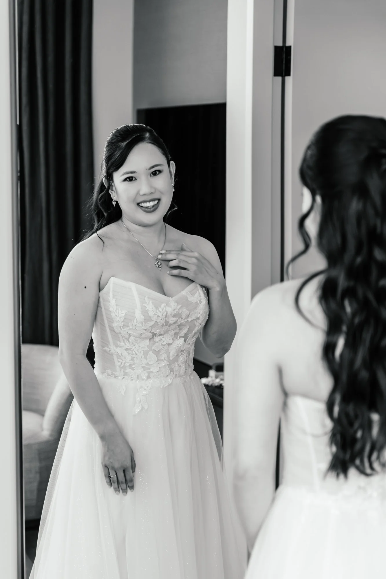 A woman in a wedding dress looking at herself in a mirror.