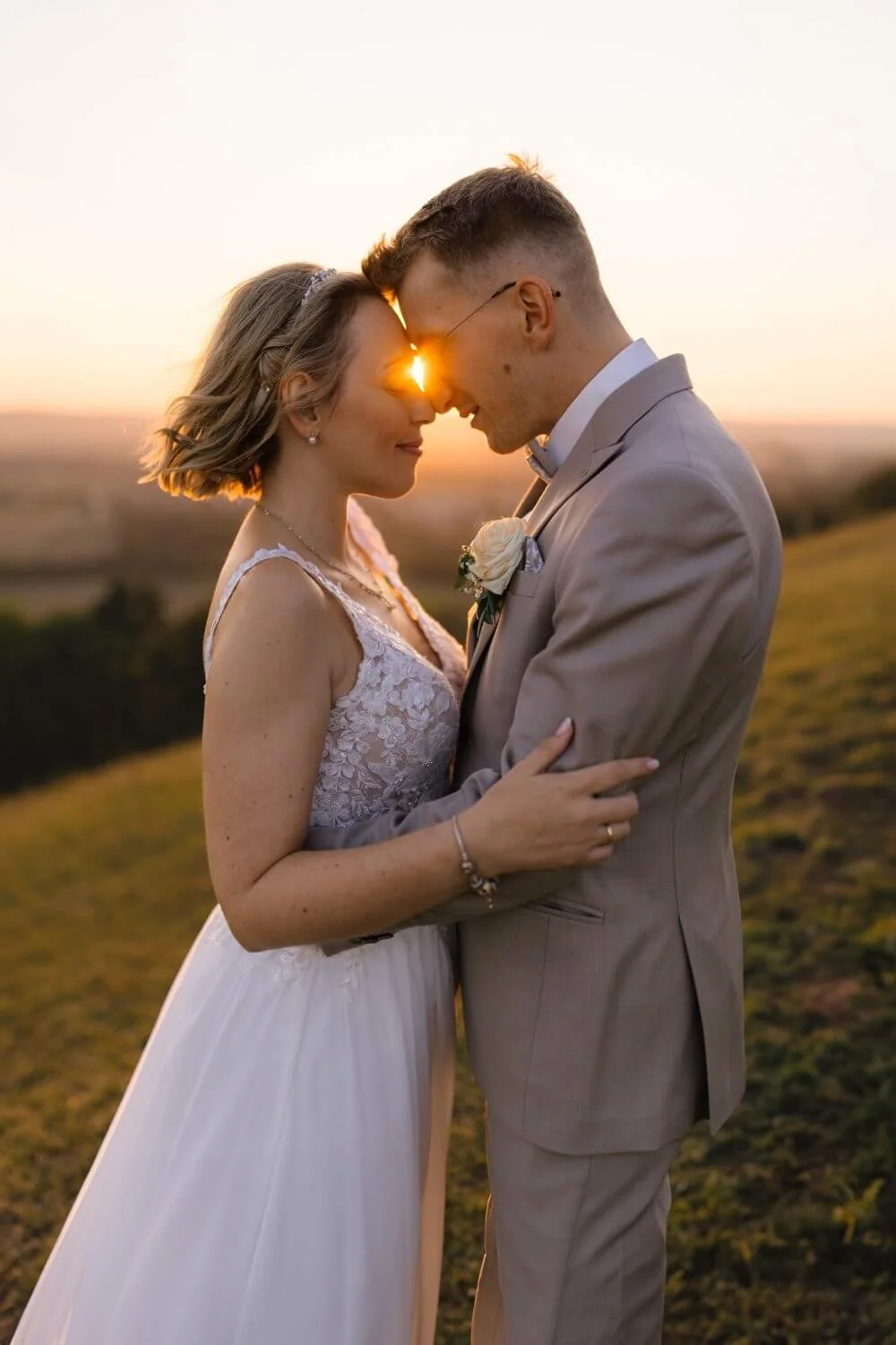 Brautpaar hält sich liebevoll im Arm und im Hintergrund ist der Sonnenuntergang zu sehen