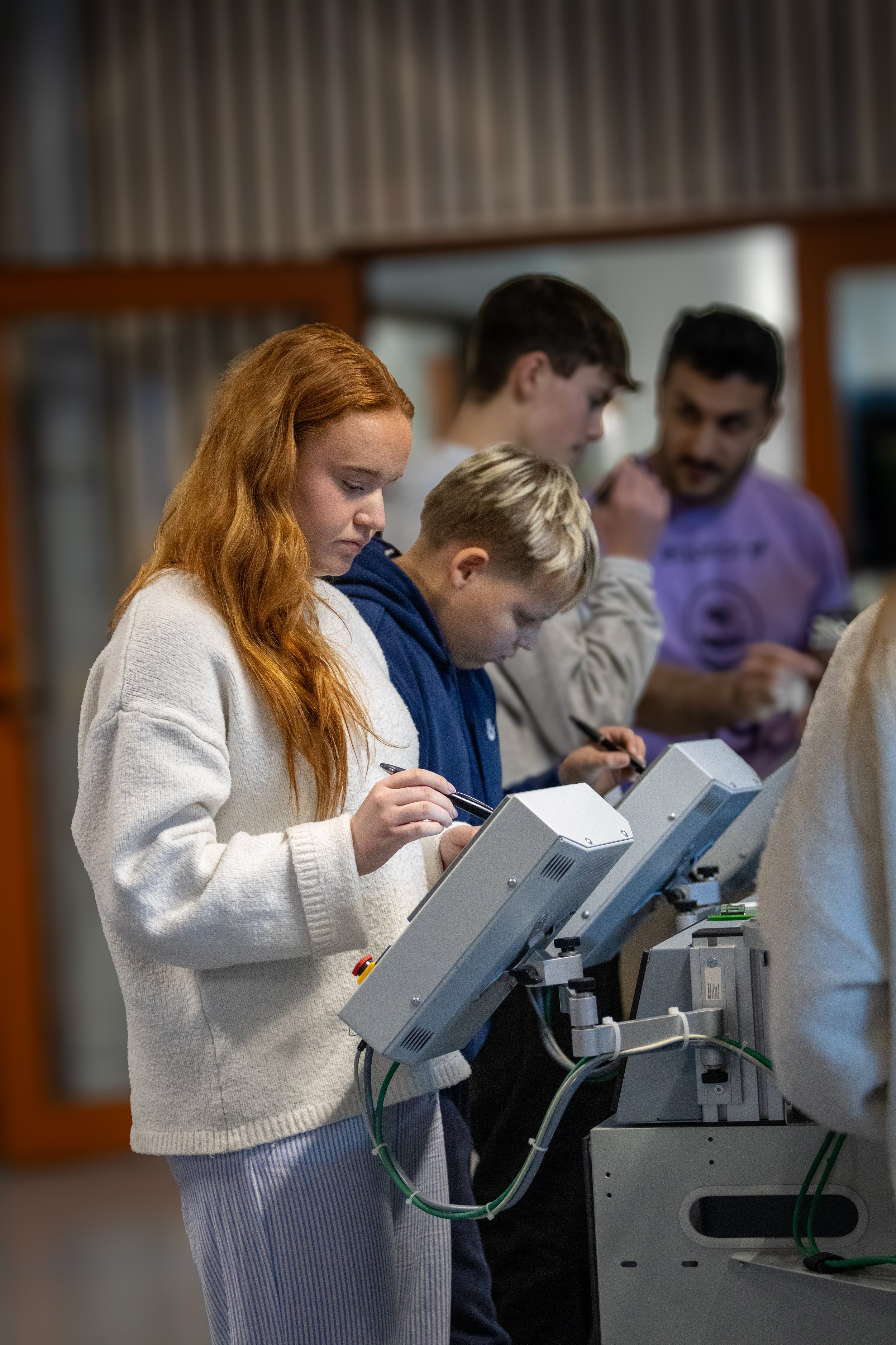 En gruppe mennesker står i en lab som bruker mikroskoper.