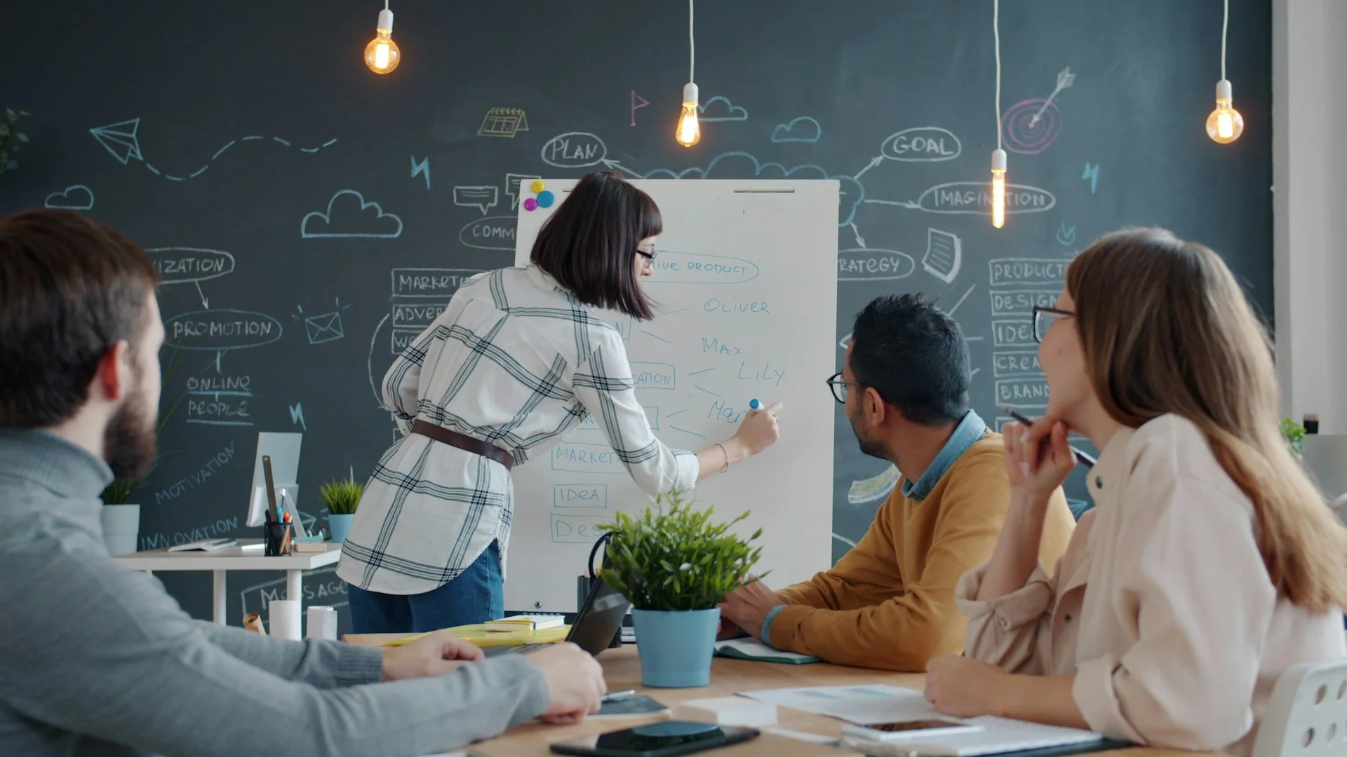 Team members discussing ideas while a colleague writes on a whiteboard.