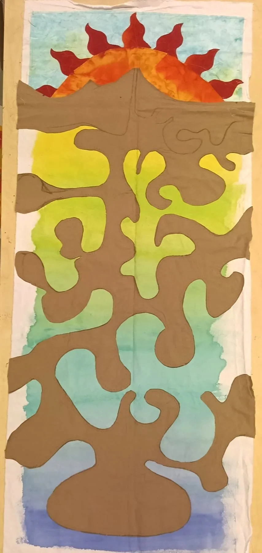 A colorful watercolor painting of a tree with a large, abstract brown trunk and branches. The background features a gradient sky with blue at the top, transitioning to green, yellow, and blue at the bottom. At the top of the painting, there are brigh