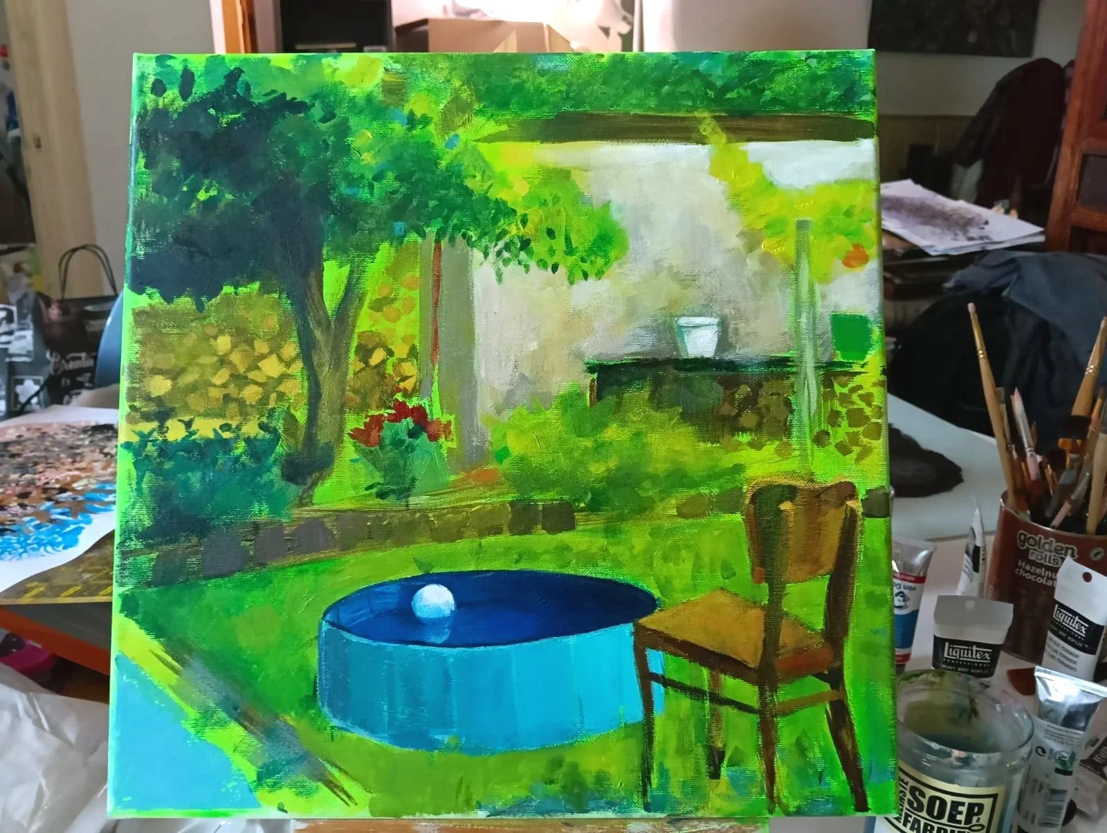 A landscape painting of a backyard scene with a tree, a pond with a ball, a chair, and a house in the background, painted in bright colors with visible brushstrokes.