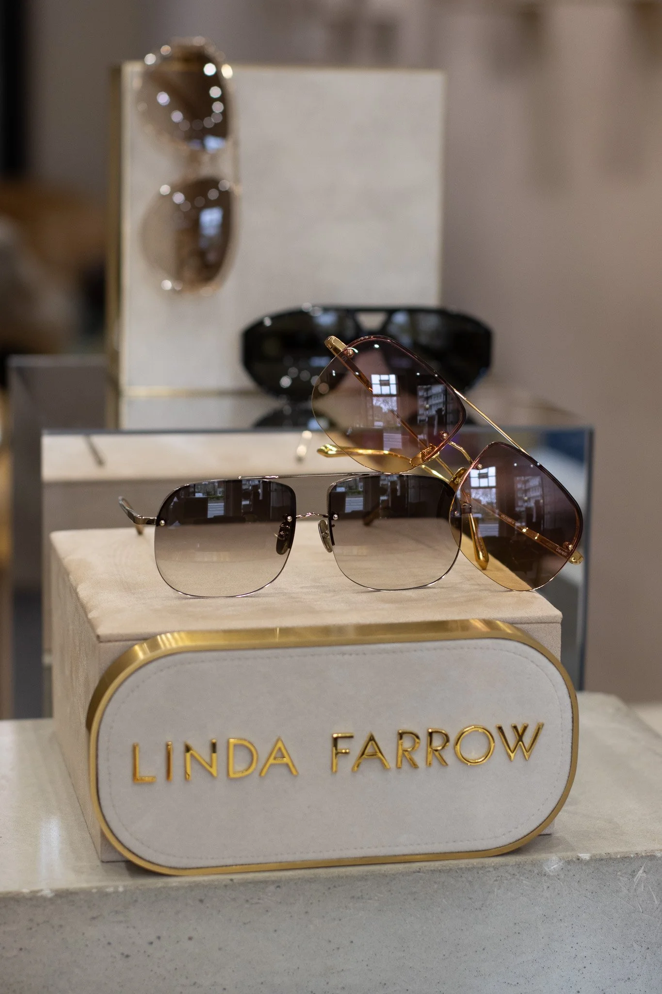 Display of sunglasses at Linda Farrow store, with a white and gold sign. Linda Farrow.