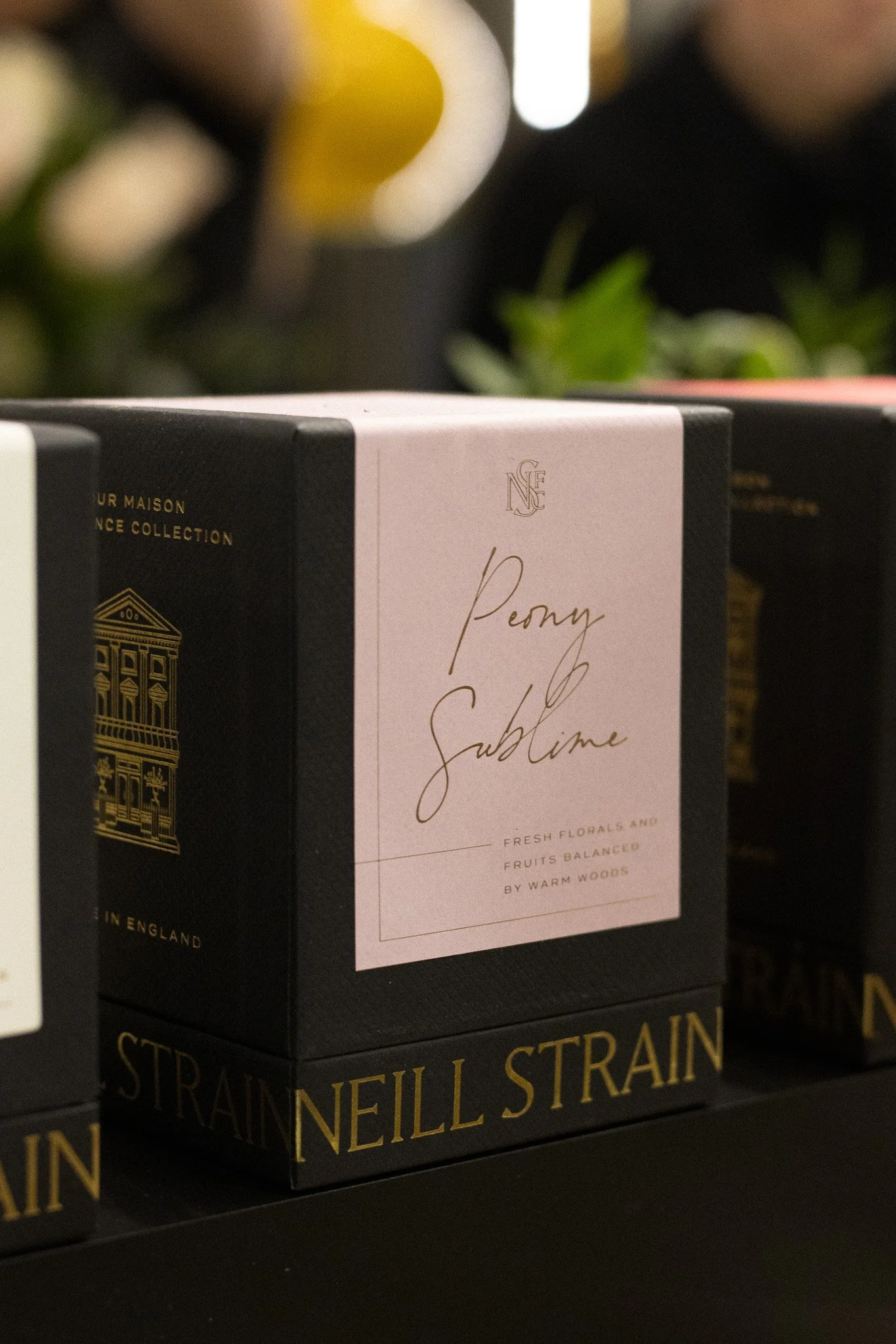 Boxes of Penylli Strain in black packaging with gold and white labels, one label reads 'Penny Sublime' and mentions floral and fruit flavors, with a gold architectural design on the box. Neill Strain, Harrods, Motcomb Street.