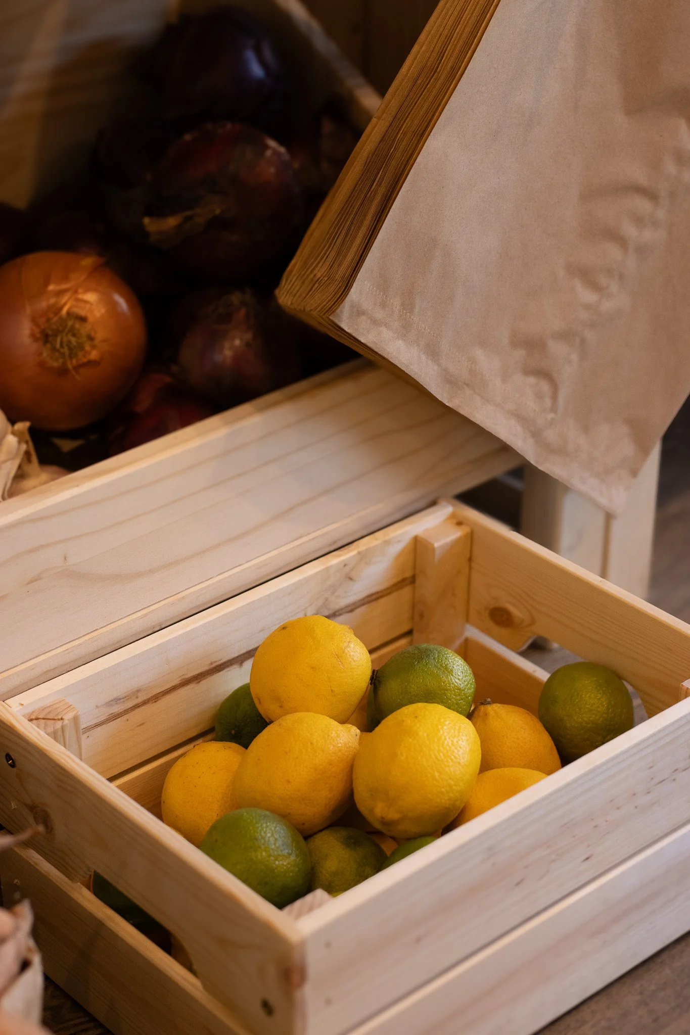Lemon and lime fruits in a wooden crate. The Cotswold Farm. 