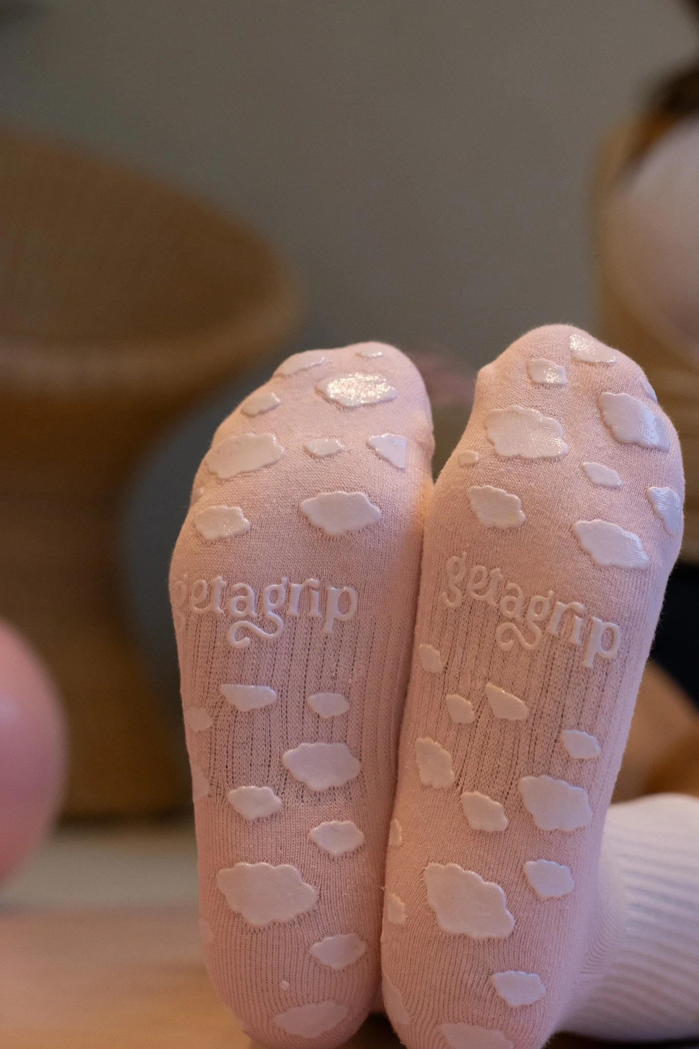 Close-up of pink socks with white heart-shaped patterns, and the word 'geargear' embroidered on them, worn by a person. Shona Manderson, Get A Grip.