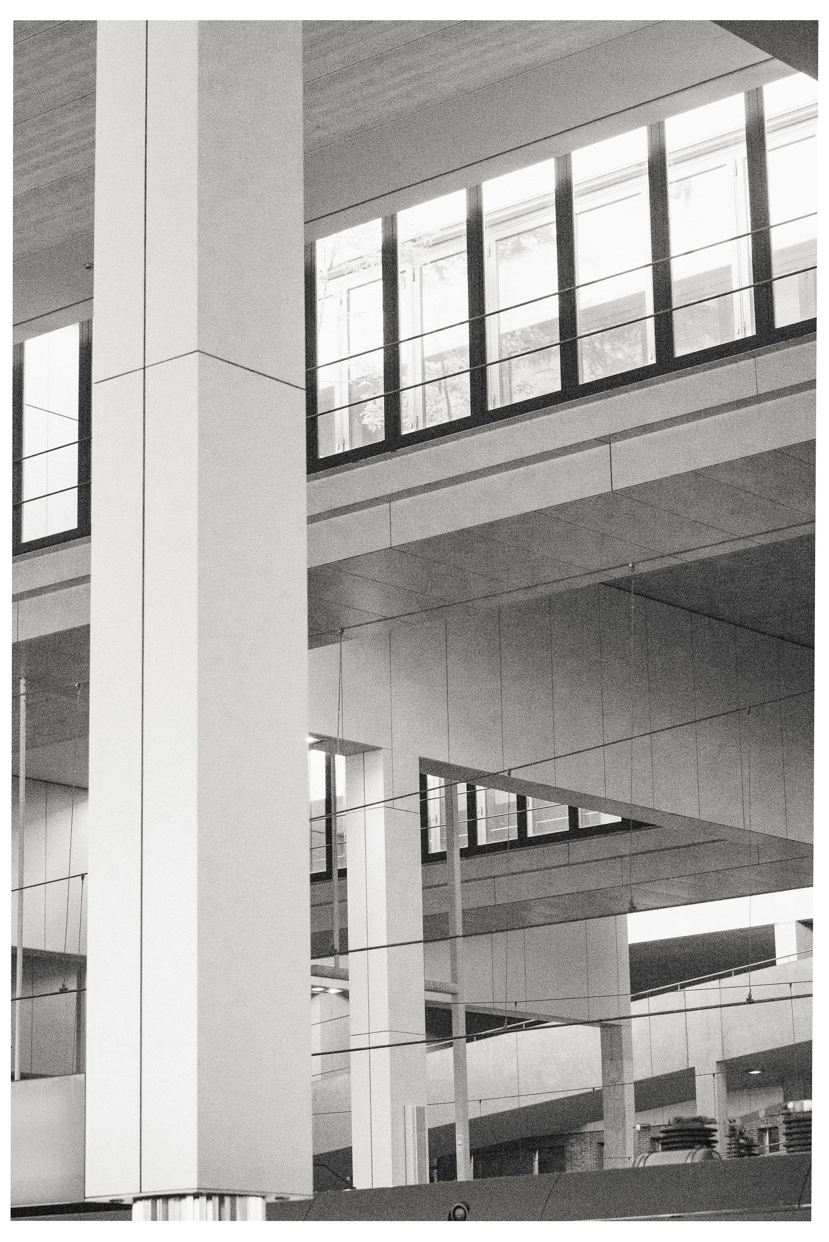 Moderne, open kantoor met meerdere verdiepingen, grote ramen, en wit/neutrale kleuren.