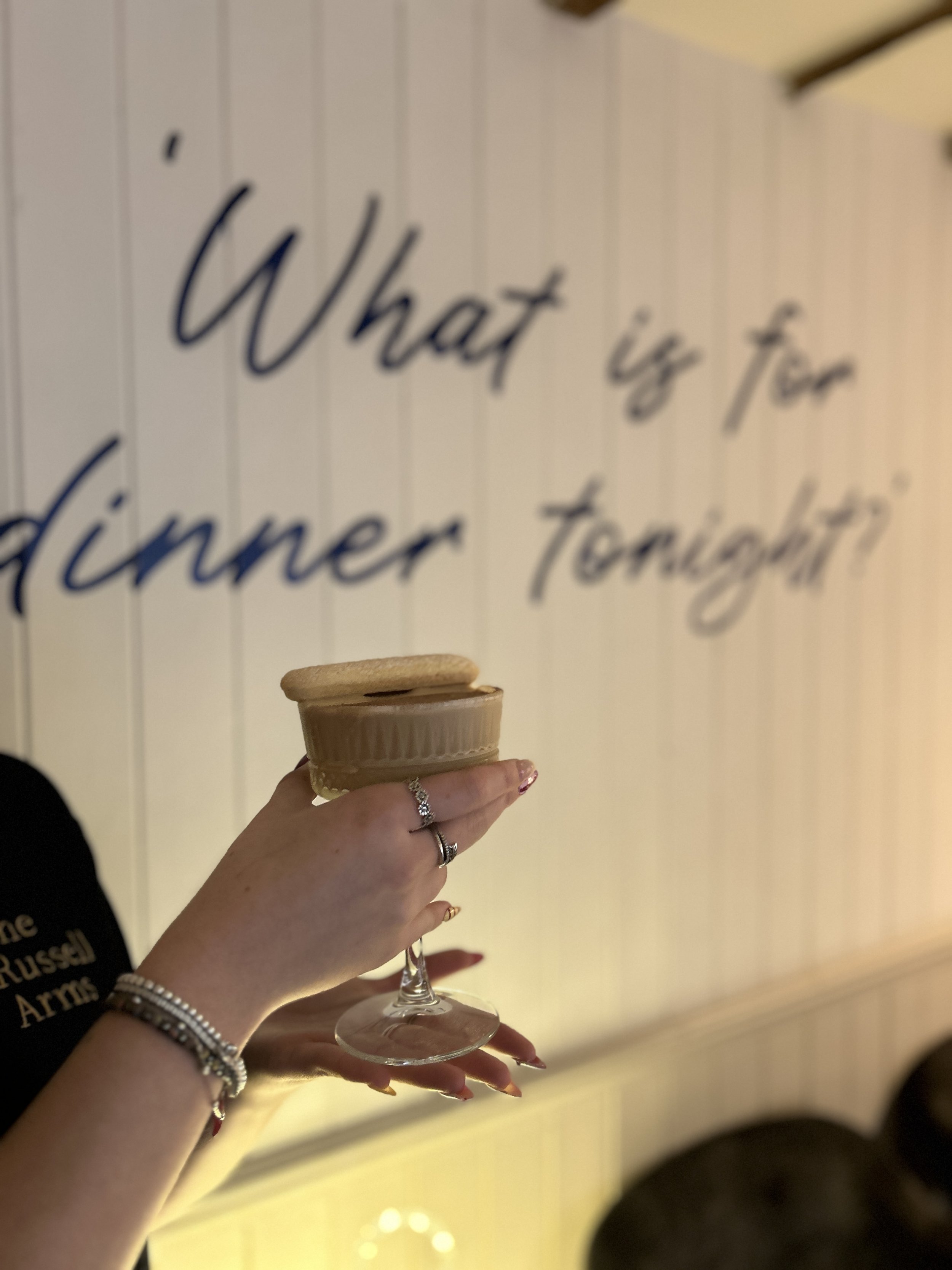 Tiramisu cocktail held in front of whats for dinner tonight sign.jpg