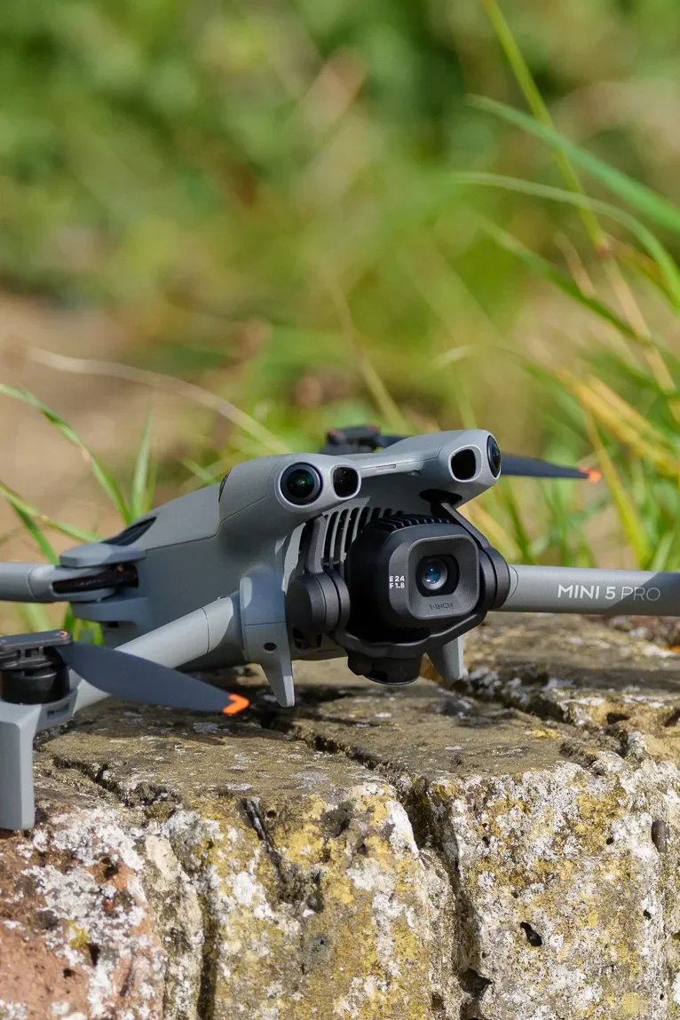 A drone flying over a blue lake with mountains in the background under a clear sky.